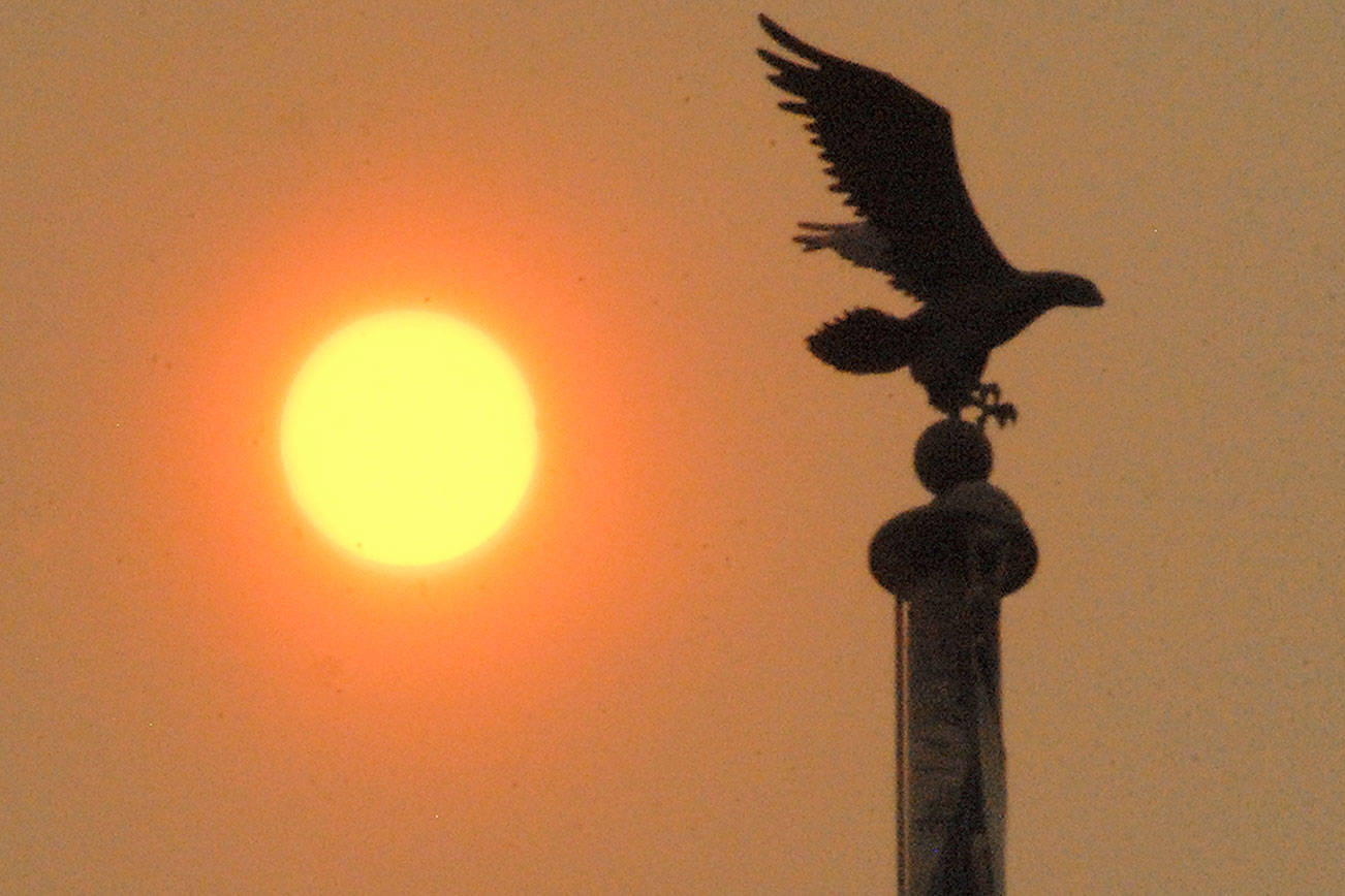 Keith Thorpe/Peninsula Daily News The sun shines behind a flagpole in front of the Clallam County Courthouse in Port Angeles at mid-morning on Tuesday as layers of smoke from wildfires in eastern Washington and Montana filter the light to shades of orange and red.