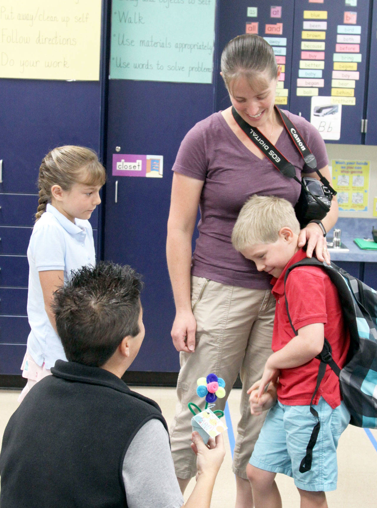 Alex Biss, right, is comforted by mom April as they meet Christine Chang, kneeling at left, Alex’s first-grade teacher at Jefferson Elementary School in Port Angeles. Paige, a third-grader, looks on for her younger brother’s special day. (Dave Logan/for Peninsula Daily News)