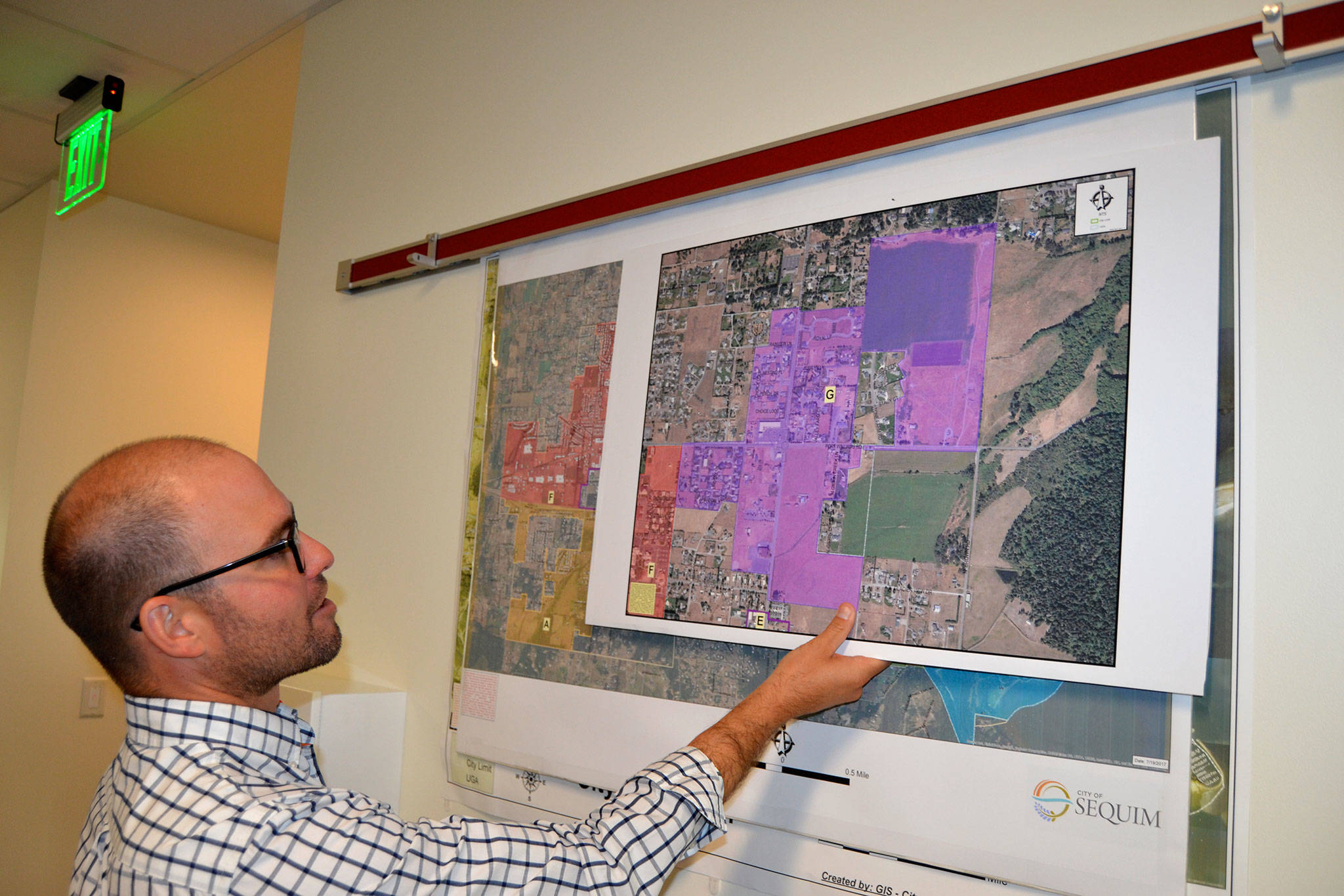 Sequim Assistant City Manager Joe Irvin holds maps of different regions in the city of Sequim on which staff members hope residents, churches and business owners will help them pinpoint issues and opportunities in their areas at a Neighborhood Visioning Meeting on Saturday in the Guy Cole Center. (Matthew Nash/Olympic Peninsula News Group)