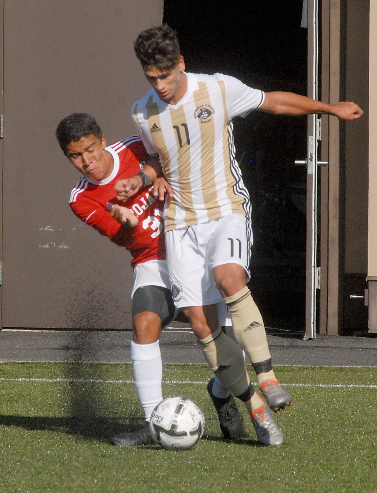 Peninsula’s Manuel Galiano, front, fends off Everett’s Juan Ortiz in first-half action on Wednesday in Port Angeles. Keith Thorpe/Peninsula Daily News