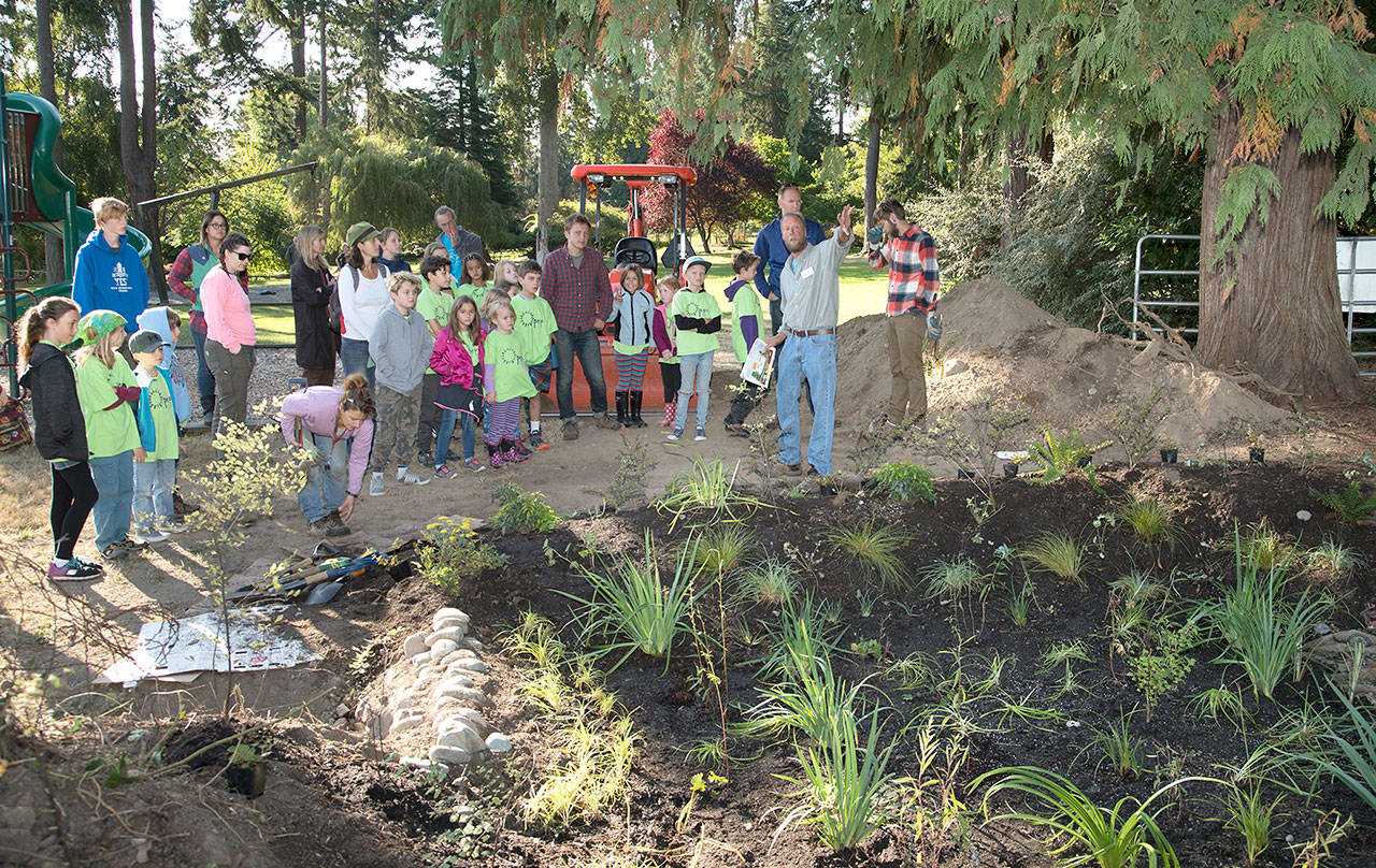 Students from Grant Street Elementary School in Port Townsend listen as Bob Simmons, water resource specialist from Washington State University, talks about the value of a rain garden like the one the group is standing next to in Chetzemoka Park. The students were participating in an alternative mulit-age program within the Port Townsend School District Friday to plant plants and mulch in the rain garden. (Steve Mullensky/for Peninsula Daily News)