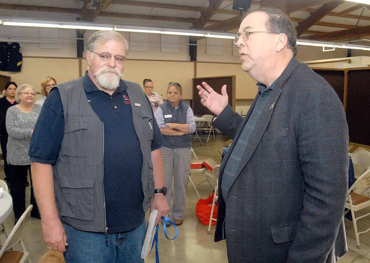 Voices for Veterans Stand Down organizer John Braasch, left, listens as AARP representative Doug Shadel speaks before presenting Braasch a certificate of appreciation for being a nominee for AARP’s Andrus Award for Community Service before Thursday’s stand-down at the Clallam County Fairgrounds in Port Angeles. (Keith Thorpe/Peninsula Daily News)