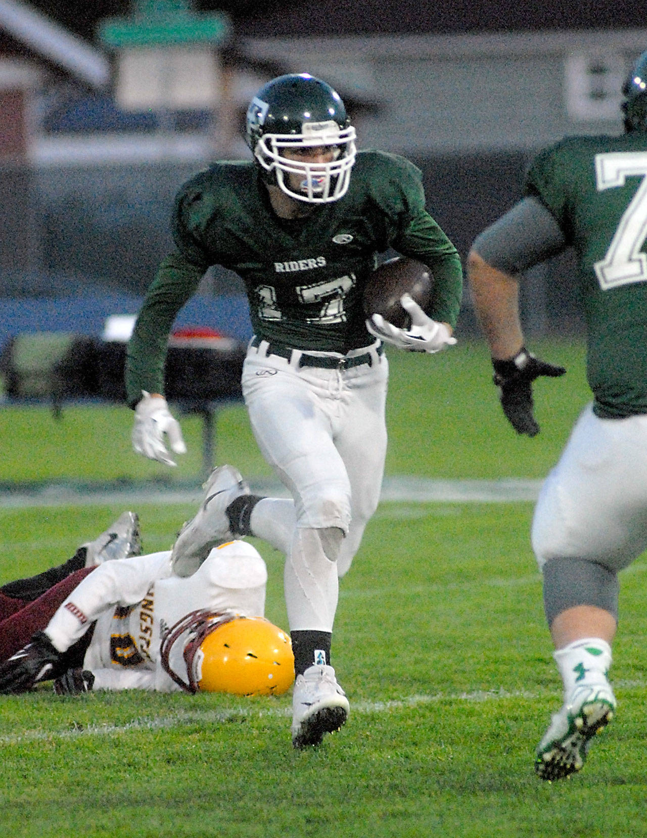 Port Angeles’ Garrett Edwards, center, evades the Kingston defense for a long gain in the first quarter on Friday at Port Angeles Civic Field.                                Keith Thorpe/Peninsula Daily News