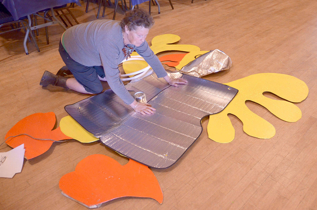 Shannon Black-Nowell puts a chicken decoration in a spacesuit to fit the theme of this year’s Kinetic Sculpture Race: “Kinetic Goes Kosmik.” (Cydney McFarland/Peninsula Daily News)