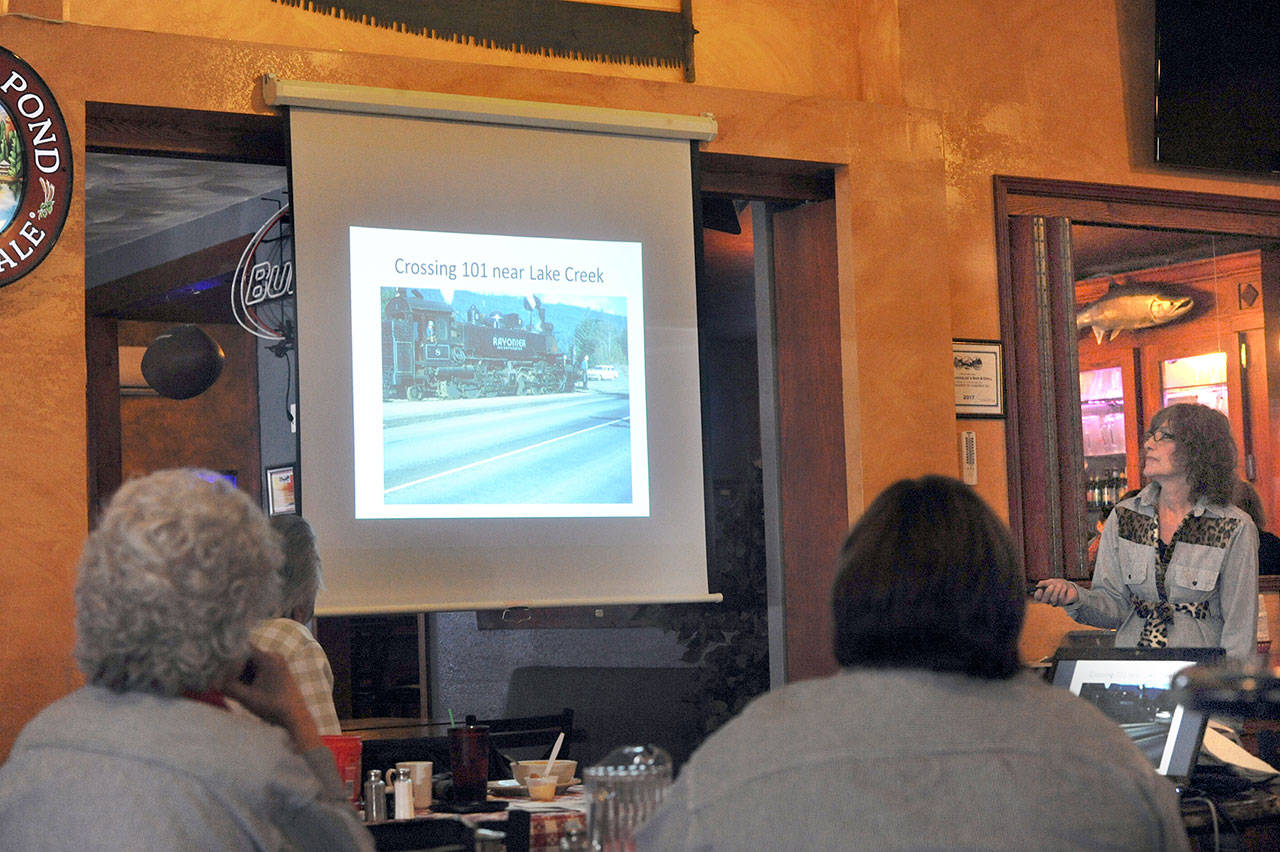 Christi Baron, right, shows a slide of the Rayonier engine crossing U.S. Highway 101 near Lake Creek north of Forks. (Lonnie Archibald/for Peninsula Daily News)