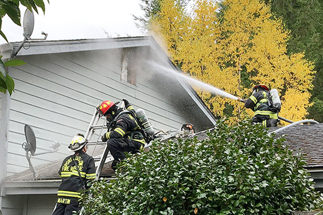Firefighters spray water at a fire through a window of a residence in the 70 block of Chimacum Creek Road on Monday morning. The fire claimed two pets, a cat and a dog. (East Jefferson Fire & Rescue)