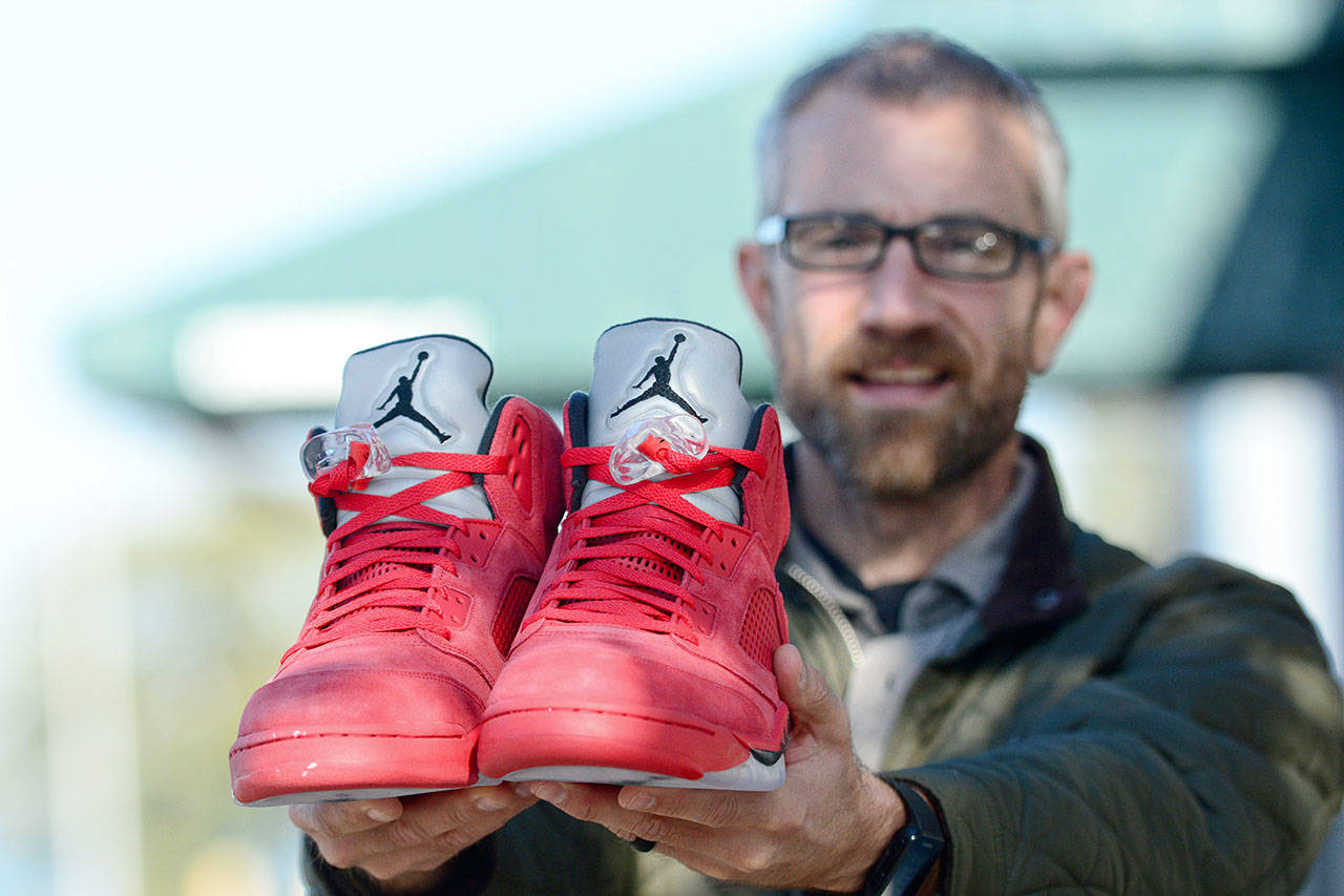 The Rev. Joe DeScala of Mended holds up a pair of Air Jordans that Mended and other community members purchased for a young tourist who had his shoes stolen from him earlier this month. (Jesse Major/Peninsula Daily News)