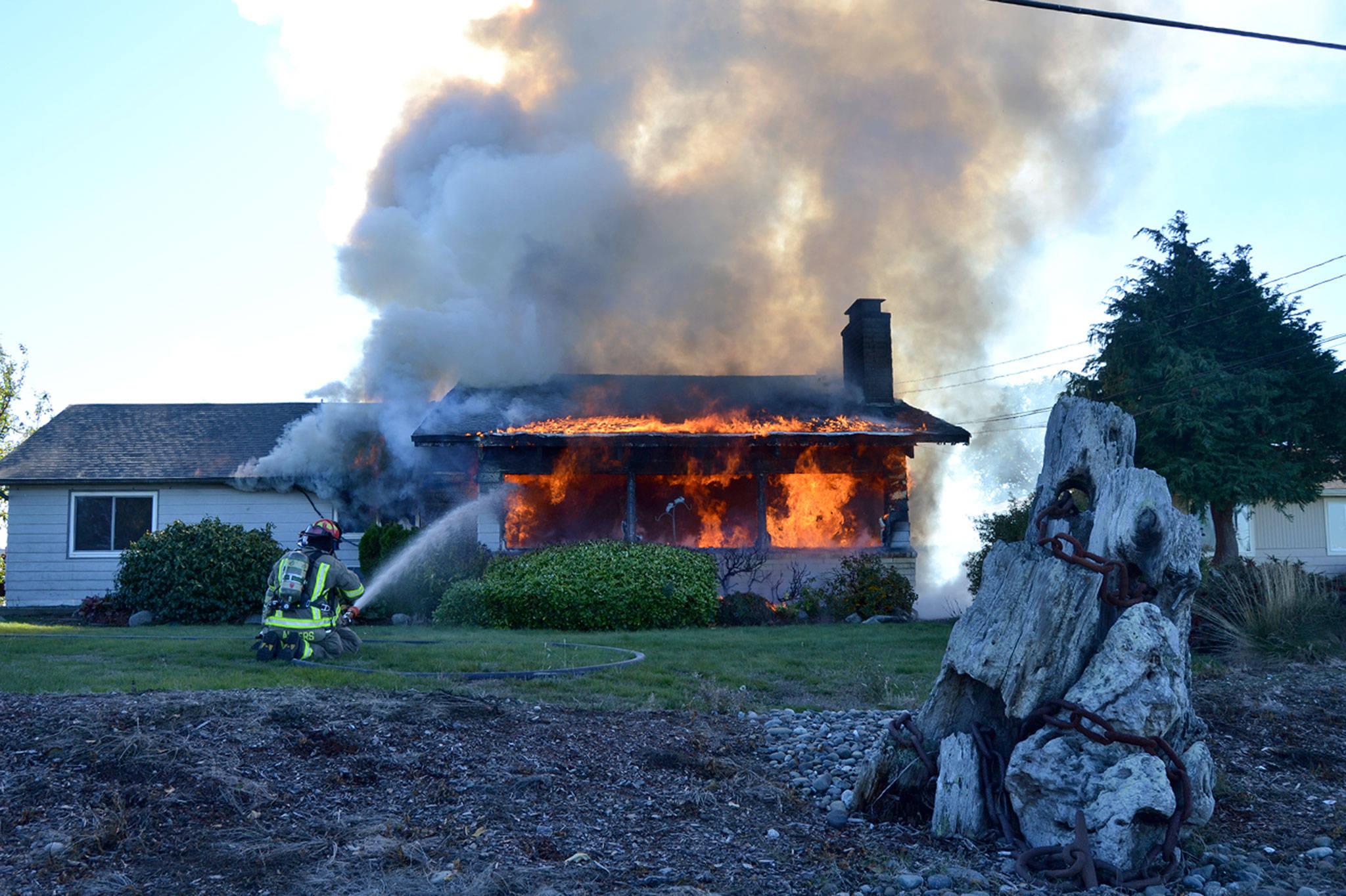 Firefighters with Clallam County Fire District No. 3 hose down the front of a home on Thornton Drive. (Matthew Nash/Olympic Peninsula News Group)