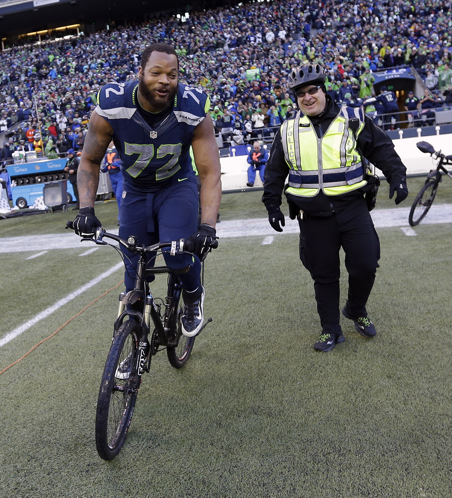 Seattle Seahawks' Michael Bennett borrows a police officer's bike after overtime of the NFL football NFC Championship game against the Green Bay Packers. (The Associated Press)