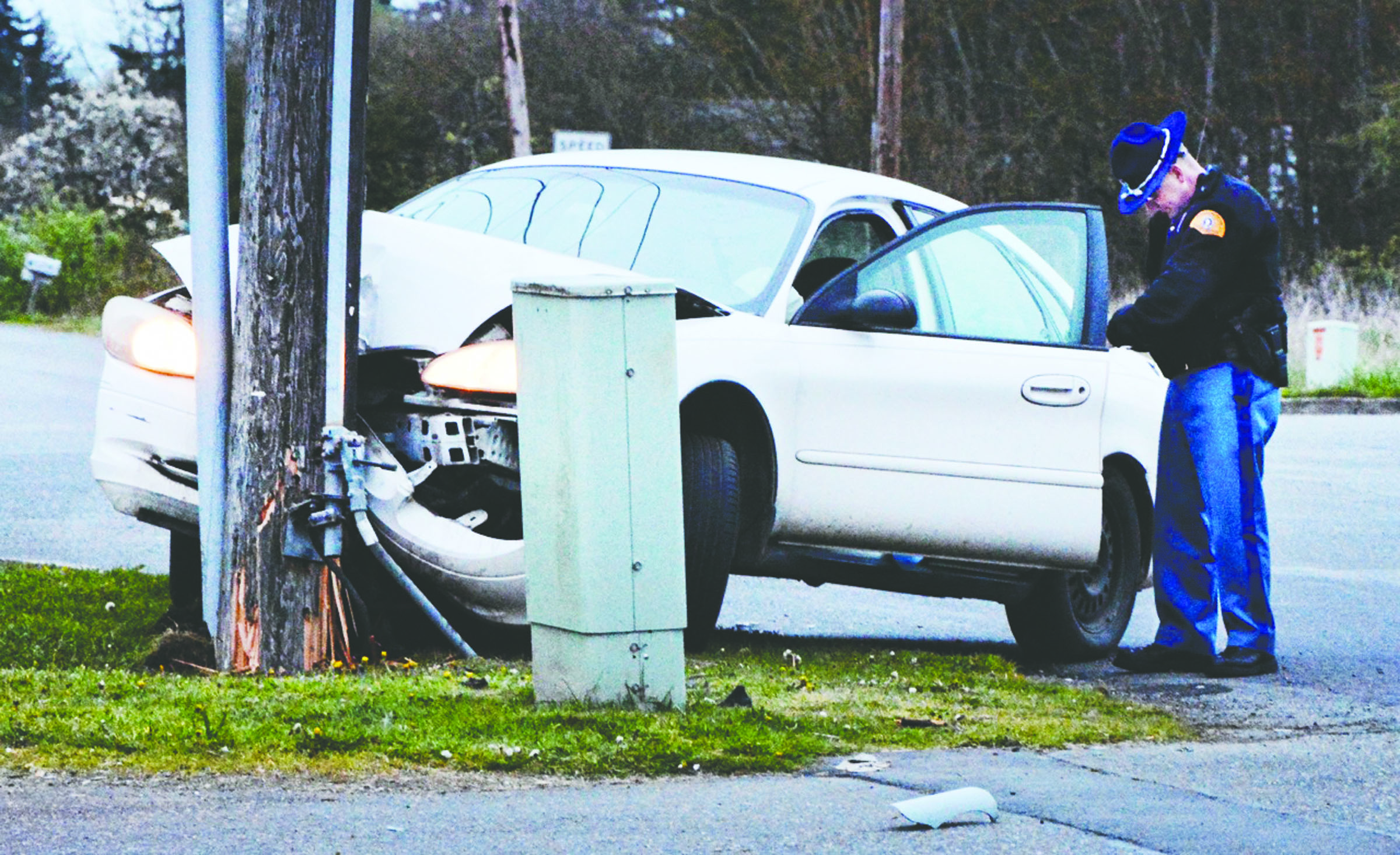 A State Trooper fills out paperwork as he examines a 2001 Ford Taurus that struck a power pole near the intersection of Mount Pleasant Road and U.S. Highway 101 on Sunday at about 7:38 p.m. The wreck cut off power to residents in the Deer Park area until noon Monday. (Jay Cline/Clallam County Fire District No. 2)