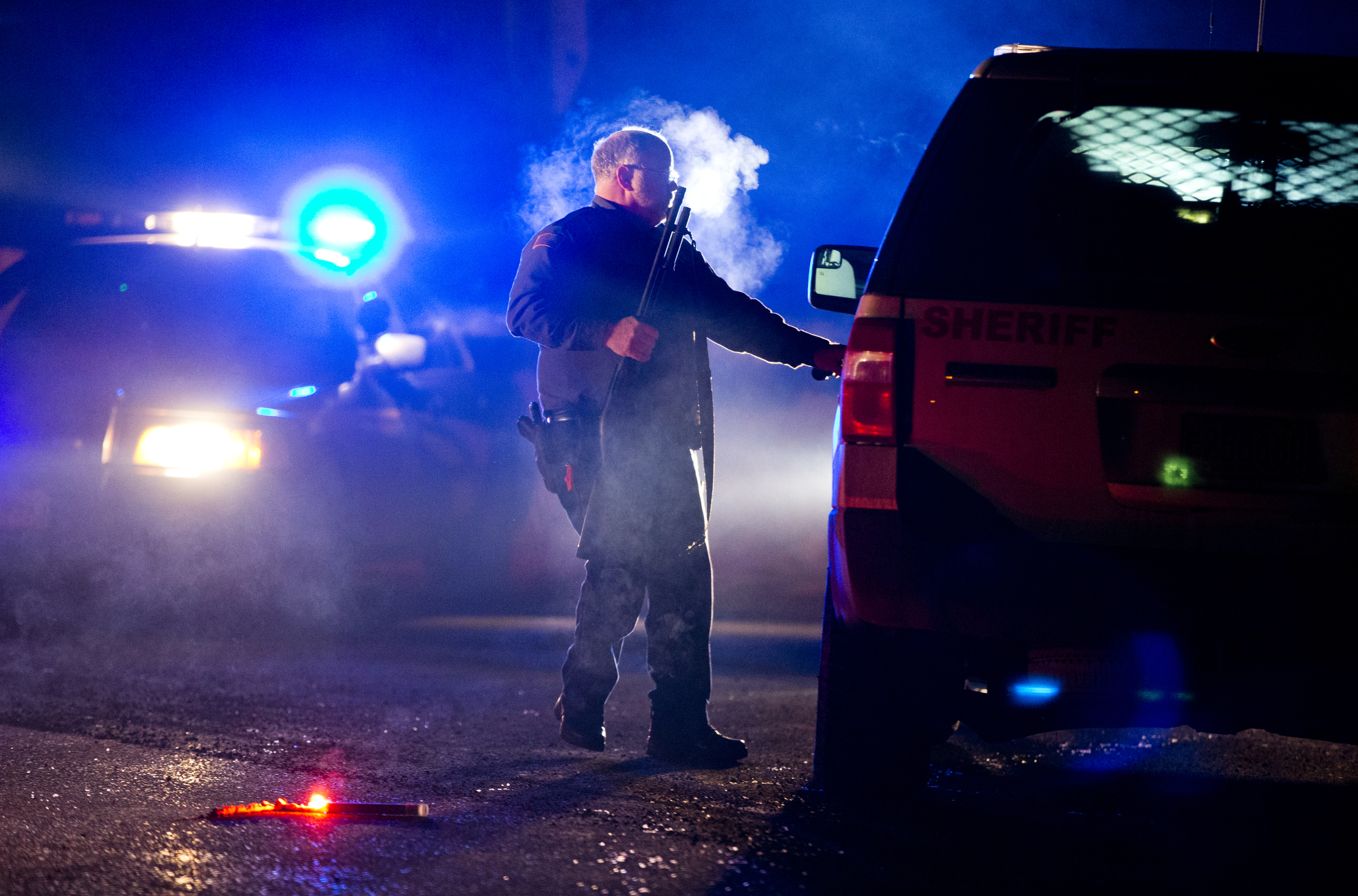 A Oregon State police officer stands by a vehicle as police officers block Highway 395 in Seneca