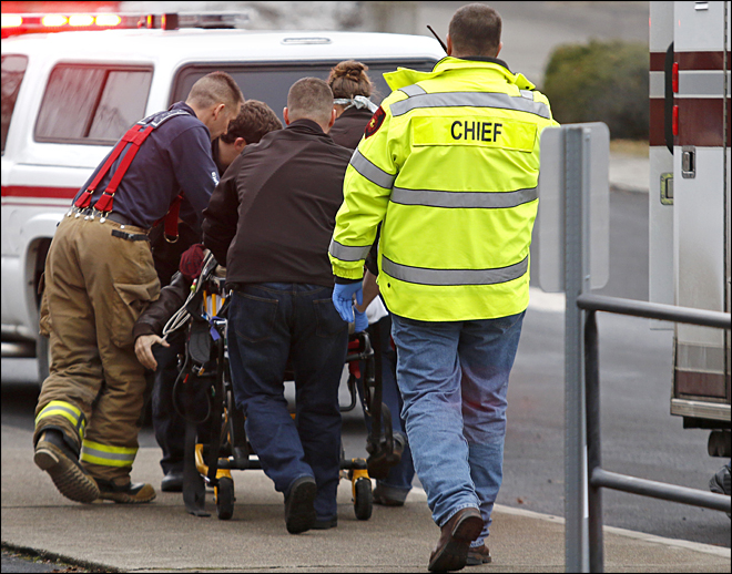Emergency medical technicians rush one of two shooting victims to an ambulance after they were shot in an office in Moscow