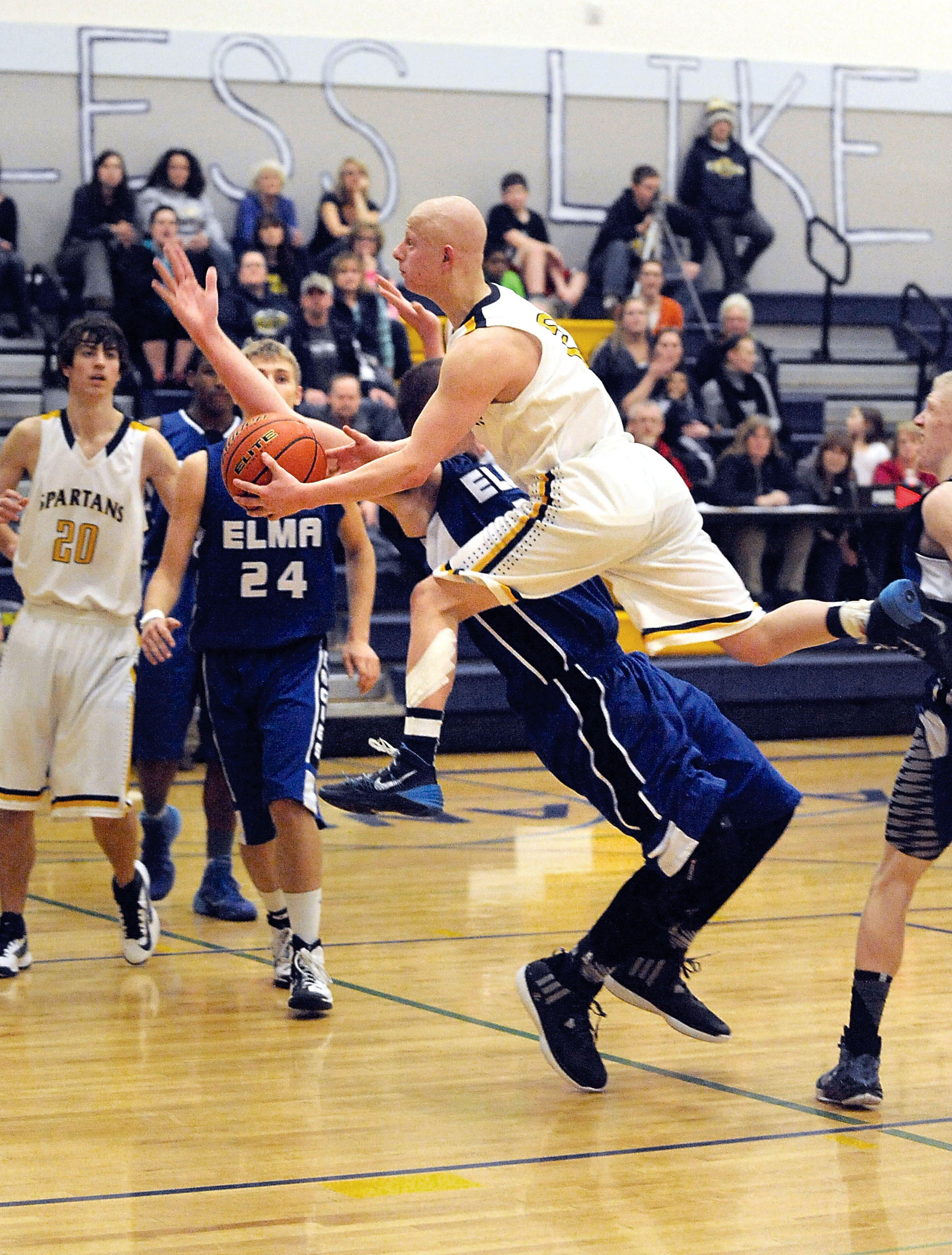 Forks' Colton Raben runs into Elma's Kolton Emerson while driving to the hoop as Forks' Peyton Rondeau (20) and Elma's Elijah Martin (24) look on. (Lonnie Archibald/for Peninsula Daily News)