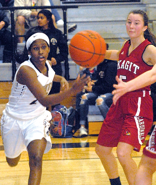Peninsula's Imani Smith passes into the lane as Skagit Valley's Jordyn Turner looks on. (Keith Thorpe/Peninsula Daily News)