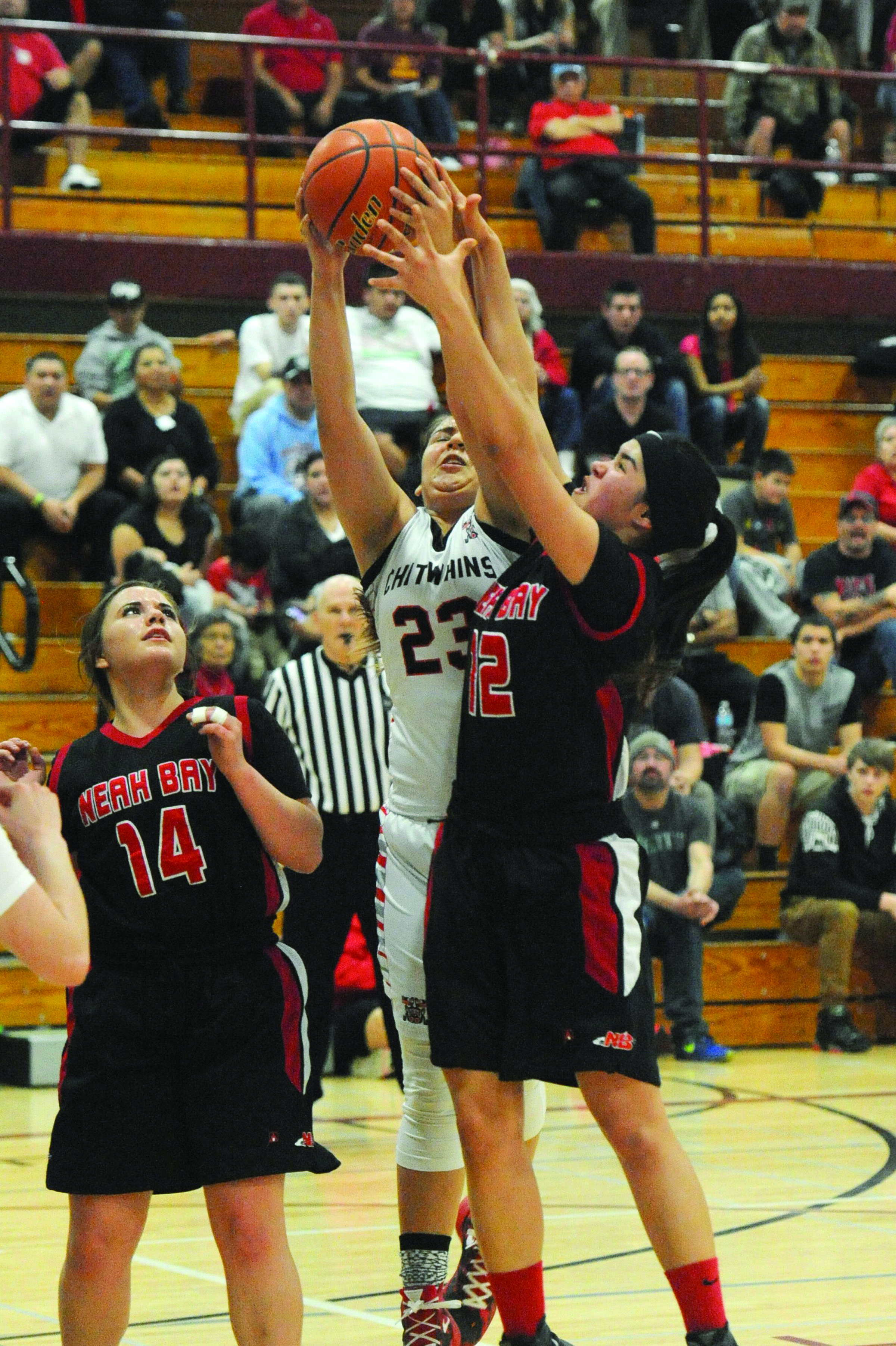 Neah Bay's Vonte Aguirre (12) challenges Taholah's Marquel Waugh for the rebound during a Class 1B basketball regional round game at W.F. West High School in Chehalis. Also in on the action is Neah Bay's Holly Greene (14). (Lonnie Archibald/for Peninsula Daily News)