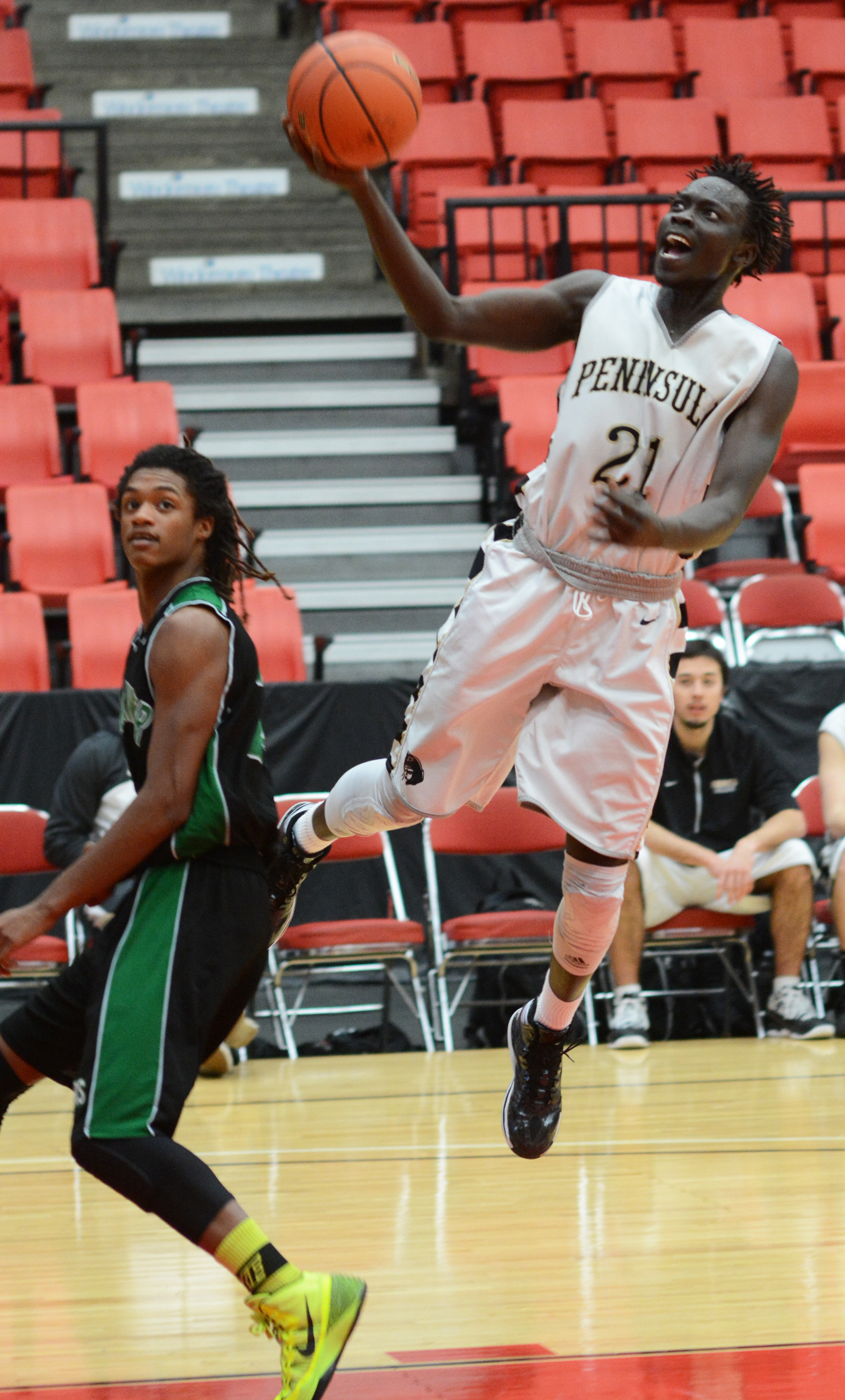 Peninsula's Jal Deng goes around Green River's Bernard Sanders for a layup. (Rick Ross/Peninsula College)