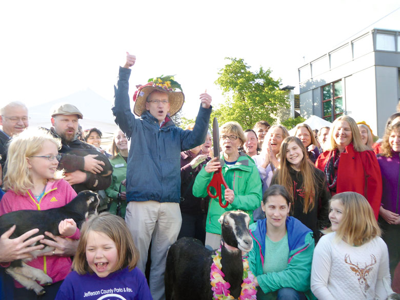 State Health Secretary John Wiesman wears a floral-bedecked hat as he cuts the ribbon to open the Port Townsend Farmers Market's 23rd season on Saturday. About 500 joined him for the market's biggest-ever opening ceremony. (Charlie Bermant/Peninsula Daily News)