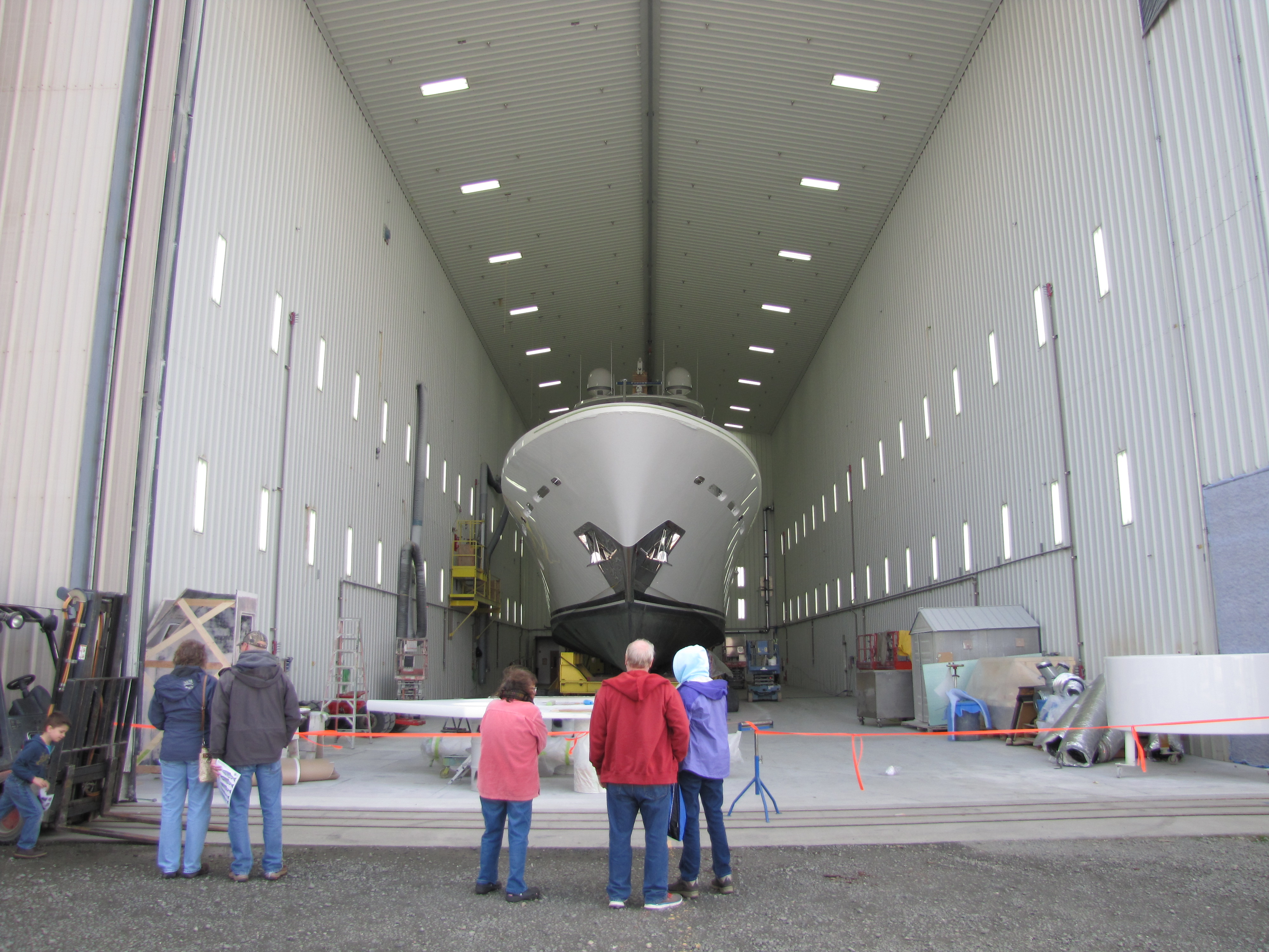 Members of a tour group gaze up at a yacht under repair in a massive Westport Yachts repair bay