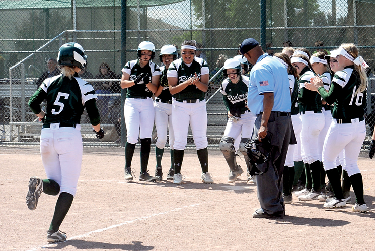 Port Angeles second baseman Natalie Steinman (5) is greeted at home plate by teammates after hitting a three-run home run against Lynden. (Lonnie Archibald/for Peninsula Daily News)