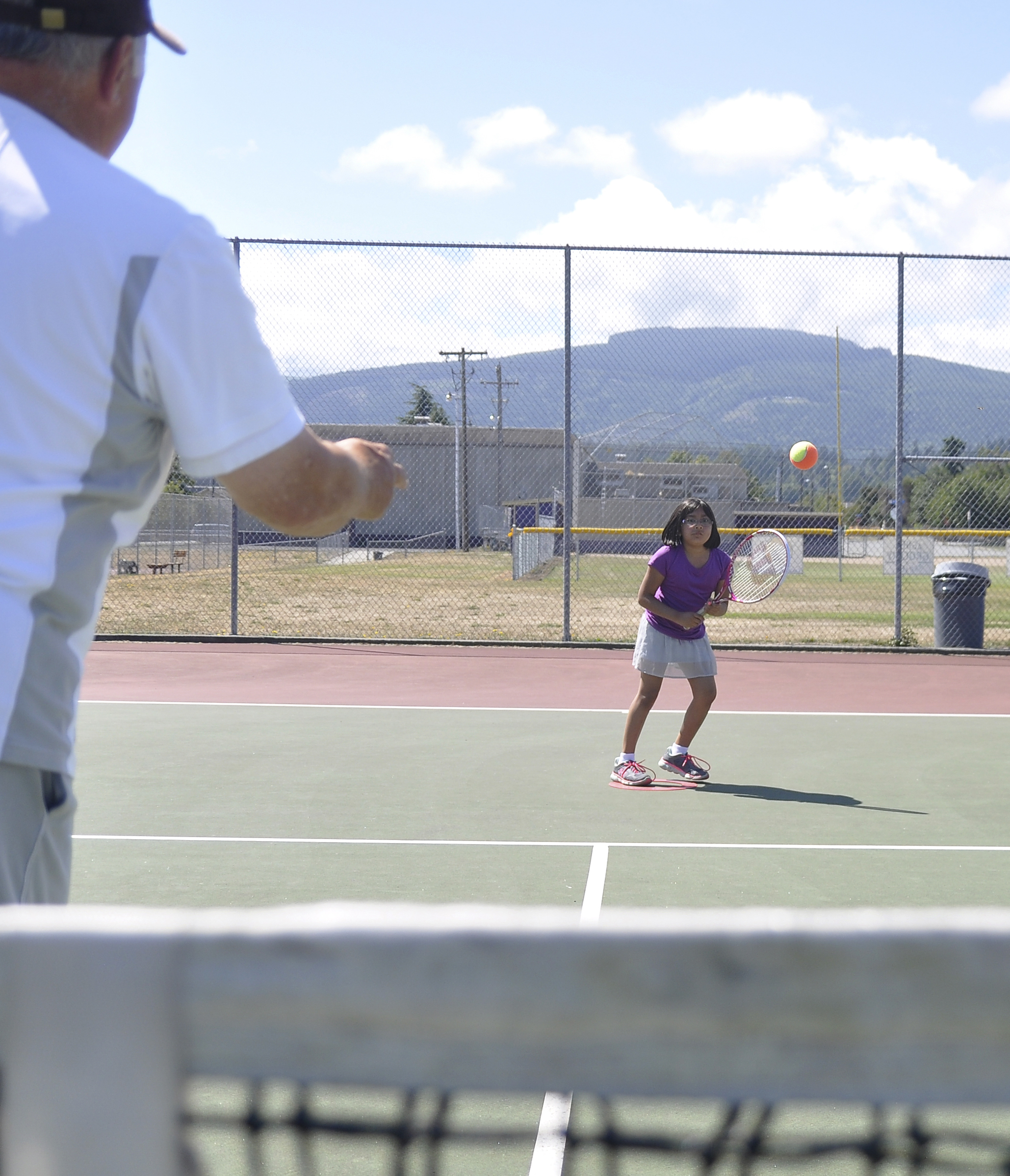 Nine-year-old Crystal Rieckhoff of Port Angeles gets instruction from tennis pro Don Thomas of Sequim at the Sequim High School tennis courts earlier this month. (Michael Dashiell/Olympic Peninsula News Group)