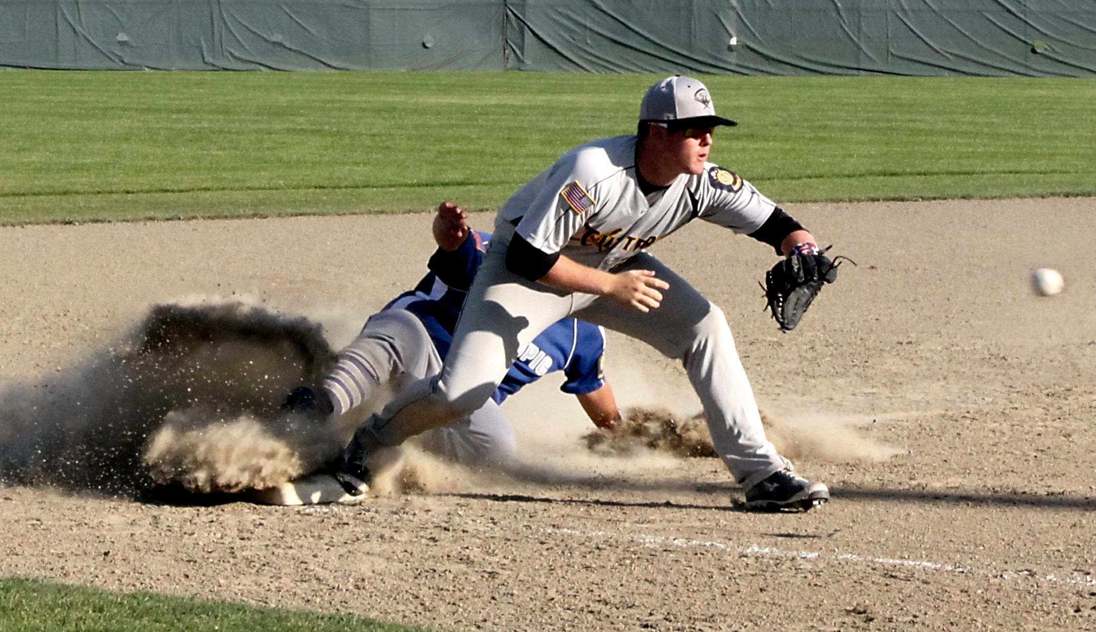 Olympic Crosscutters third baseman Lane Dotson prepares to catch a throw as Olympic Tigers base runner Tommy Fernandez slides safely into third base at Civic Field last month. Dave Logan/for Peninsula Daily News