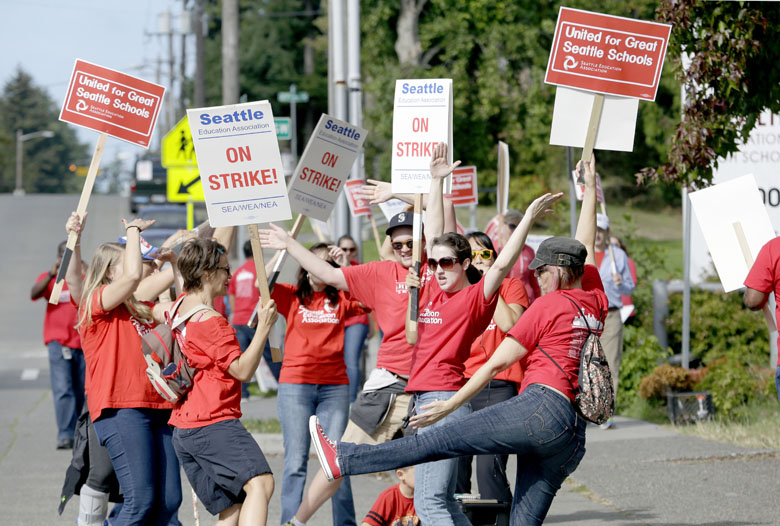 Teachers dance and cheer next to a picket line Wednesday in front of Chief Sealth International High School in Seattle. The Associated Press