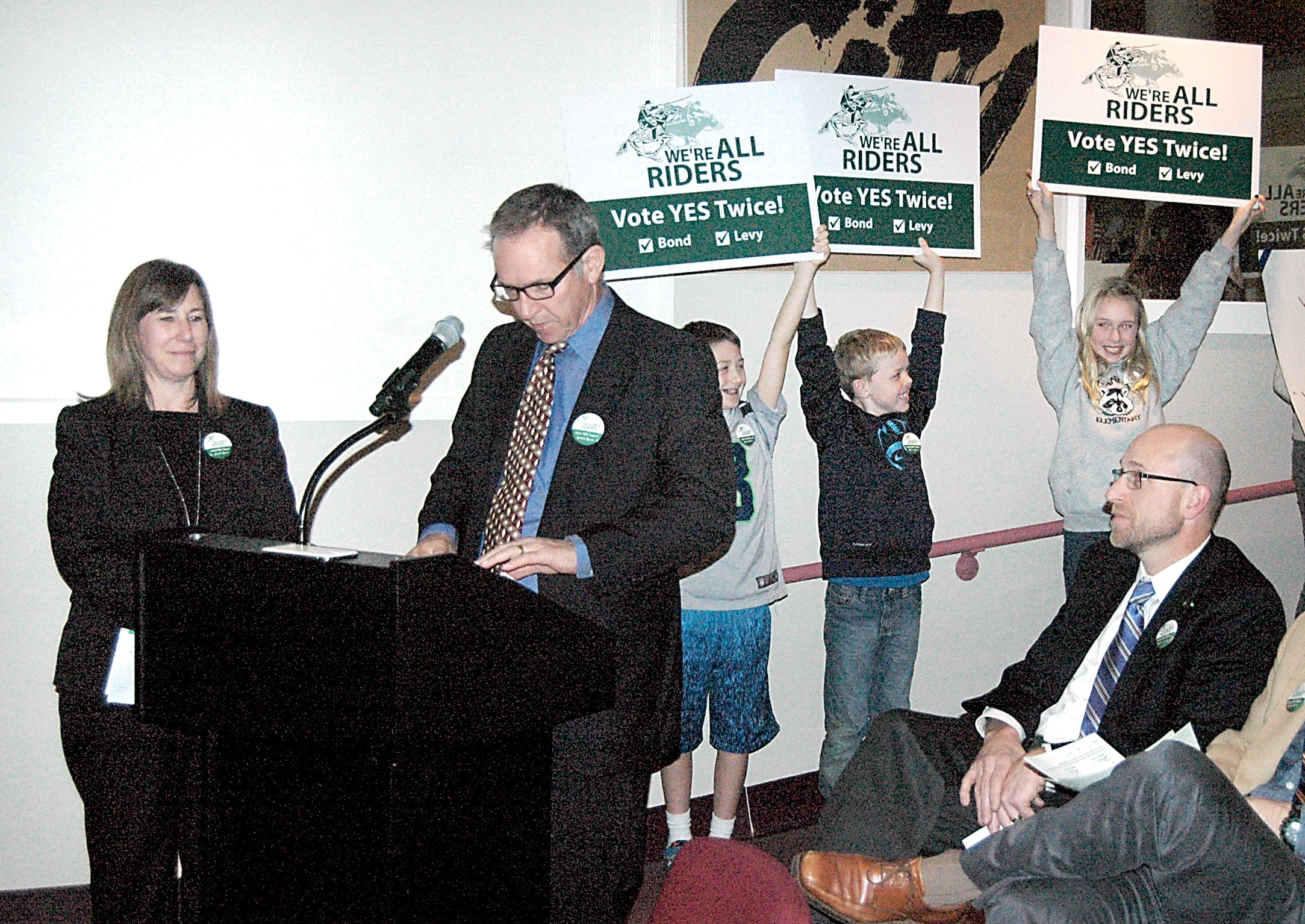 Port Angeles School District Director of Finance and Operations Kelly Pearson and Schools Superintendent Marc Jackson give presentations Tuesday to the Port Angeles City Council on the proposed Feb. 10 school district bond and levy special election as schoolchildren hold up campaign signs.  —Photo by Paul Gottlieb/Peninsula Daily News ()