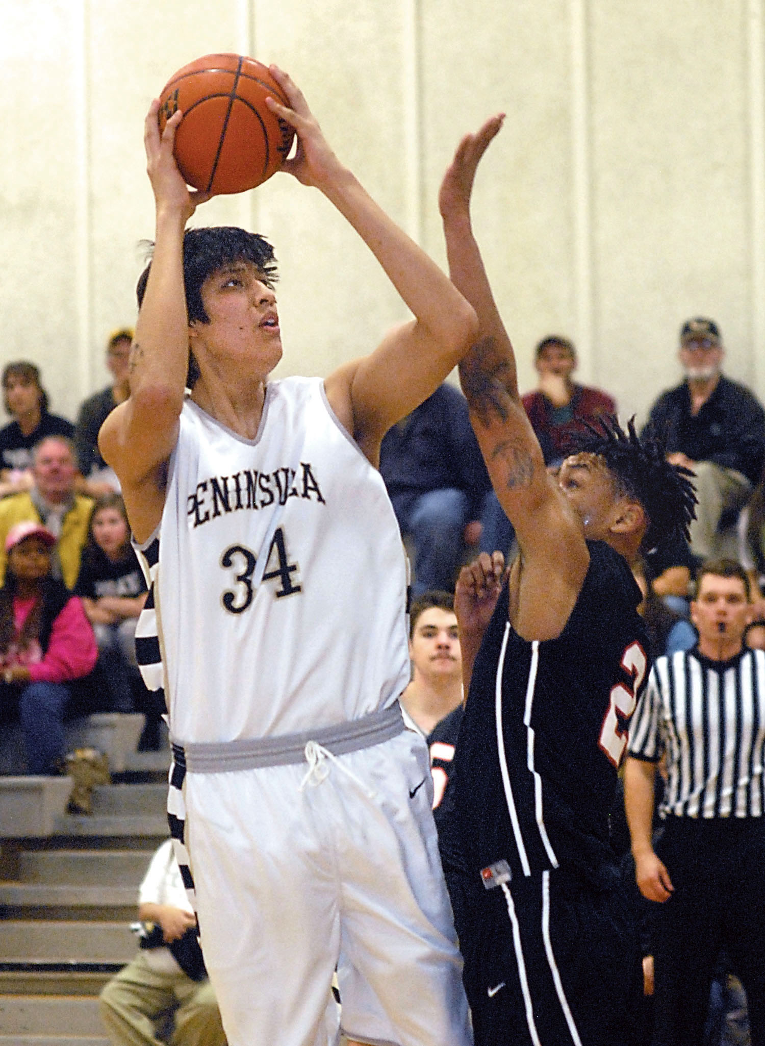 Peninsula's Jonah Cook aims for the hoop as Olympic's Cortavious Williams defends the lane. (Keith Thorpe/Peninsula Daily News)
