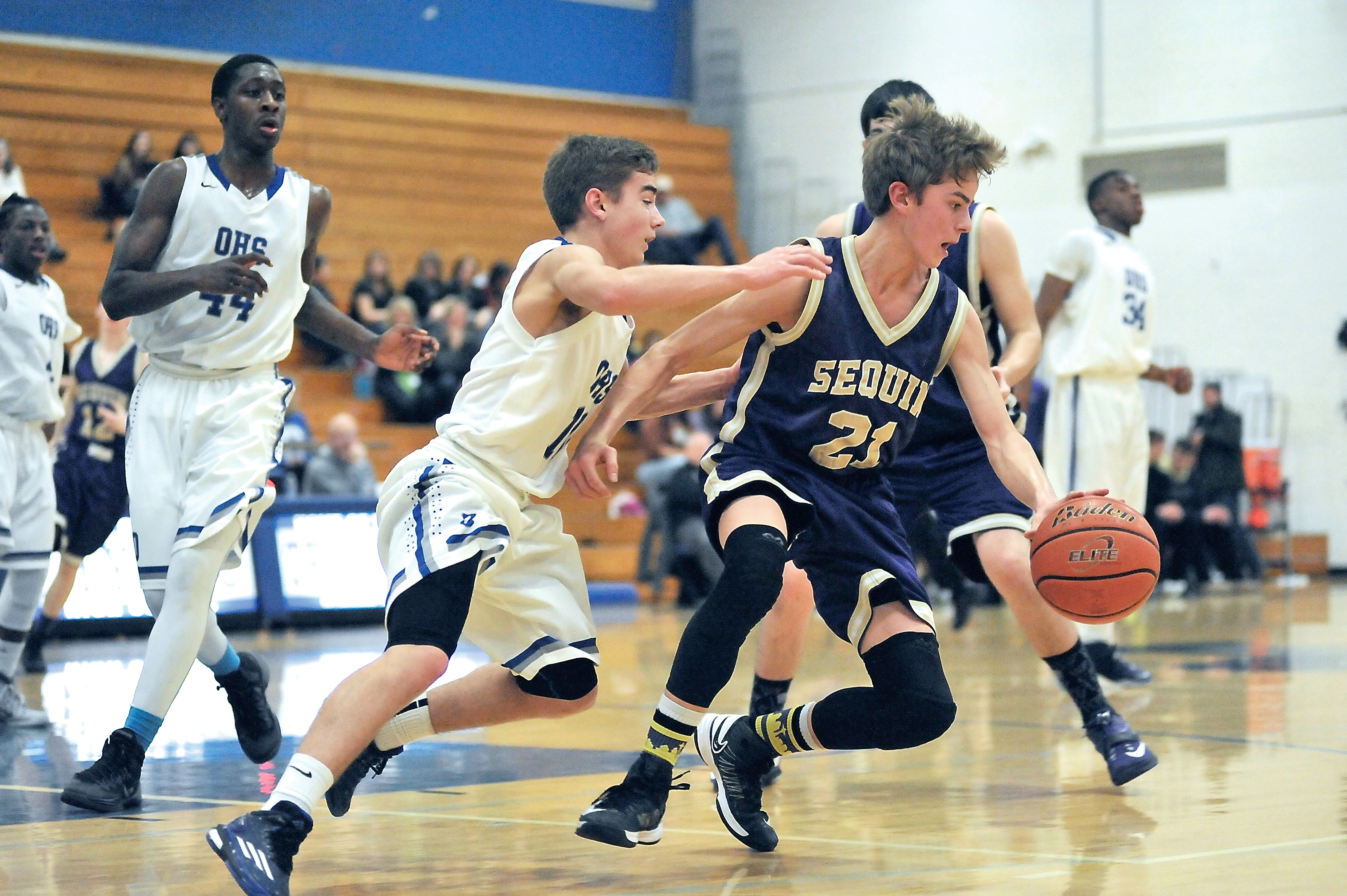 Sequim's Jackson Oliver dribbles against the defense of Olympic's Erik Turnquist. Oliver scored 11 points in the Wolves' 51-39 road win. (Jeff Halstead/for Peninsula Daily News)