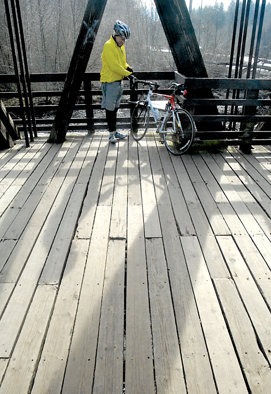 Bicyclist Mark Langeberg of Sequim takes a break on the original main span over the Dungeness River at Railroad Bridge Park in Sequim on Tuesday. — Keith Thorpe/Peninsula Daily News ()