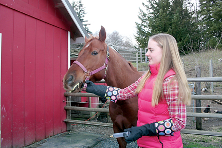 Silver Spurs 4-H member Sophie Marchant administers a syringe full of crushed antibiotics mashed with feed into her horse Trooper’s mouth — elevating his head and jaw until he swallows it — three times daily to help combat a mass in his abdomen quite possibly caused by a severe cut in his stomach a few years ago. — Karen Griffiths/for Peninsula Daily News ()