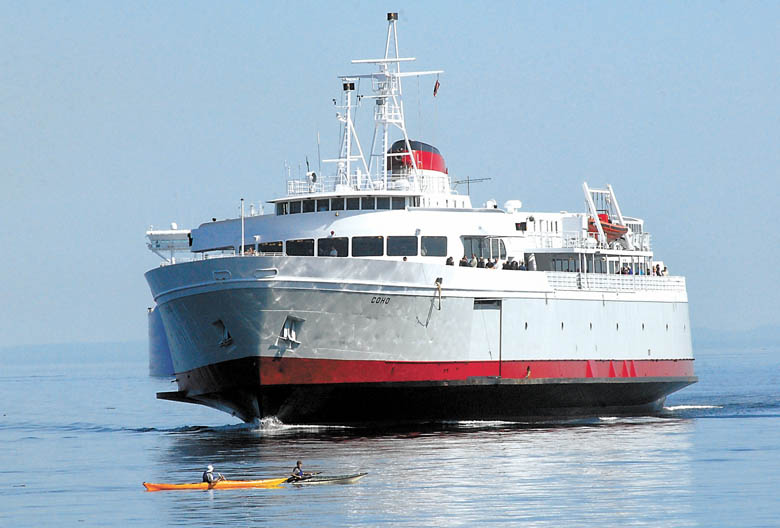 A pair of kayakers paddle in Port Angeles Harbor as the MV Coho approaches. — Keith Thorpe/Peninsula Daily News ()