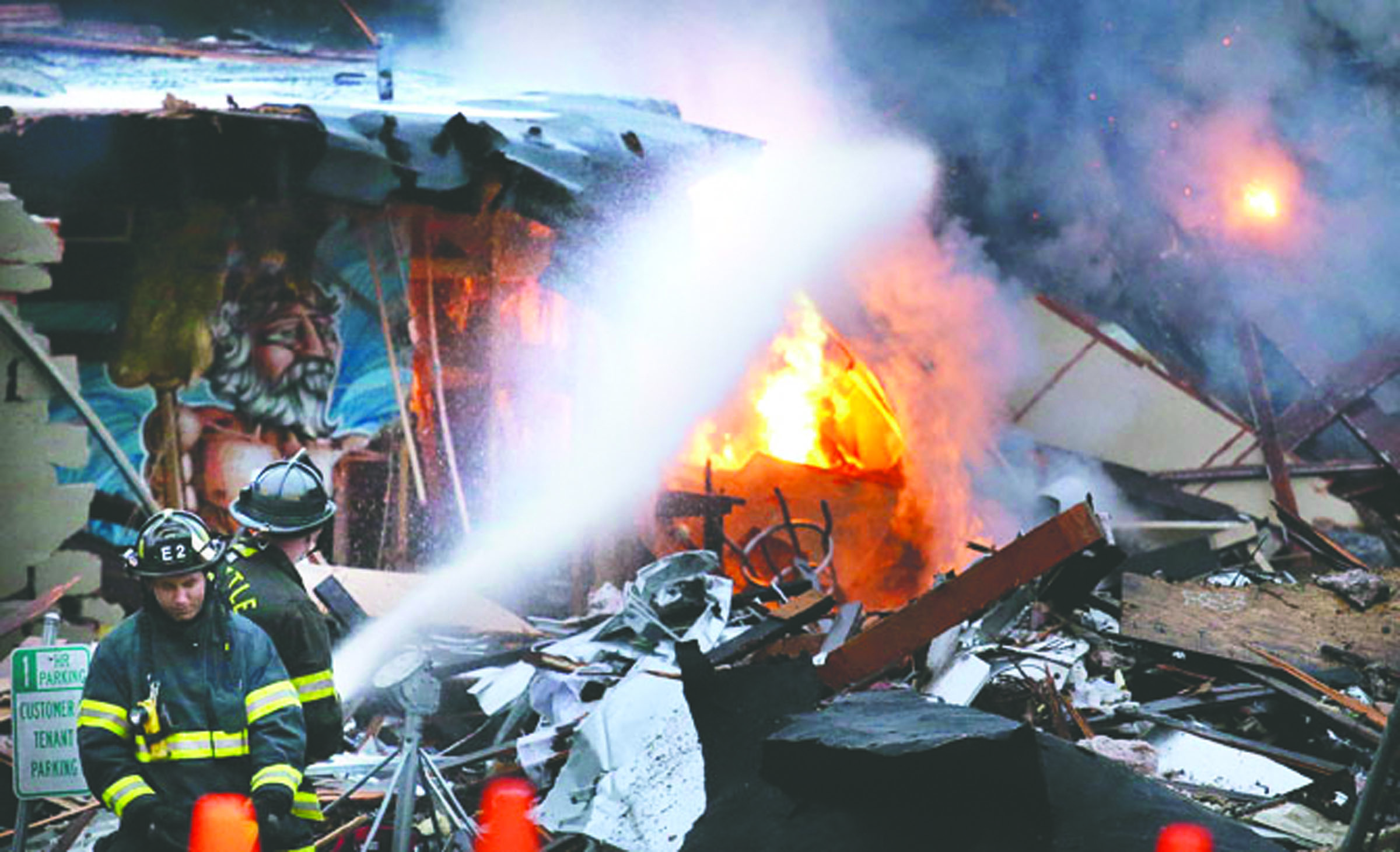Firefighters hose down on flames burning in the rubble left from an early morning explosion Wednesday in Seattle. (The Associated Press)