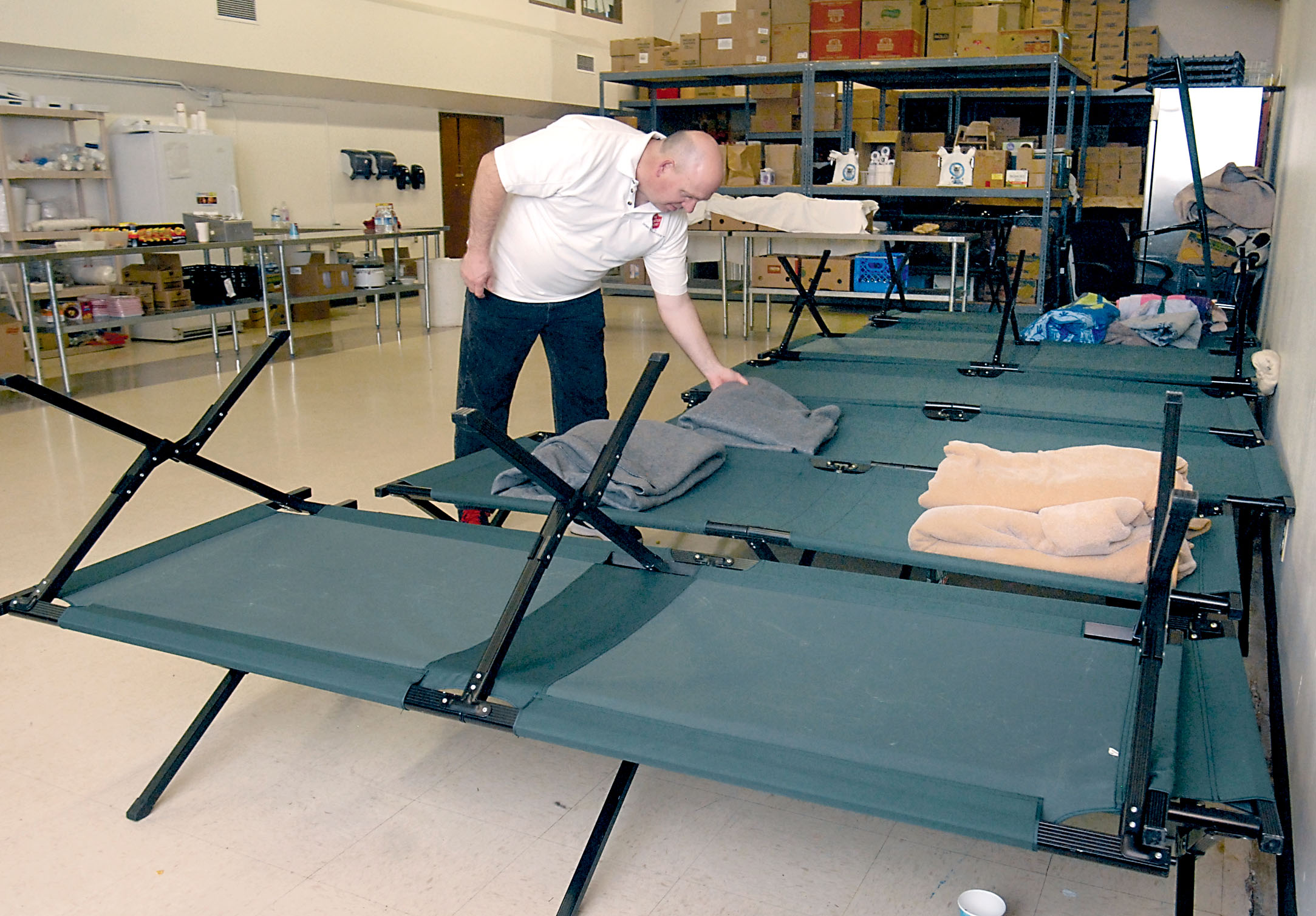Salvation Army Maj. Scott Ramsey places a blanket on a cot used for an emergency shelter in the organization’s Peabody Street headquarters in Port Angeles. — Keith Thorpe/Peninsula Daily News ()