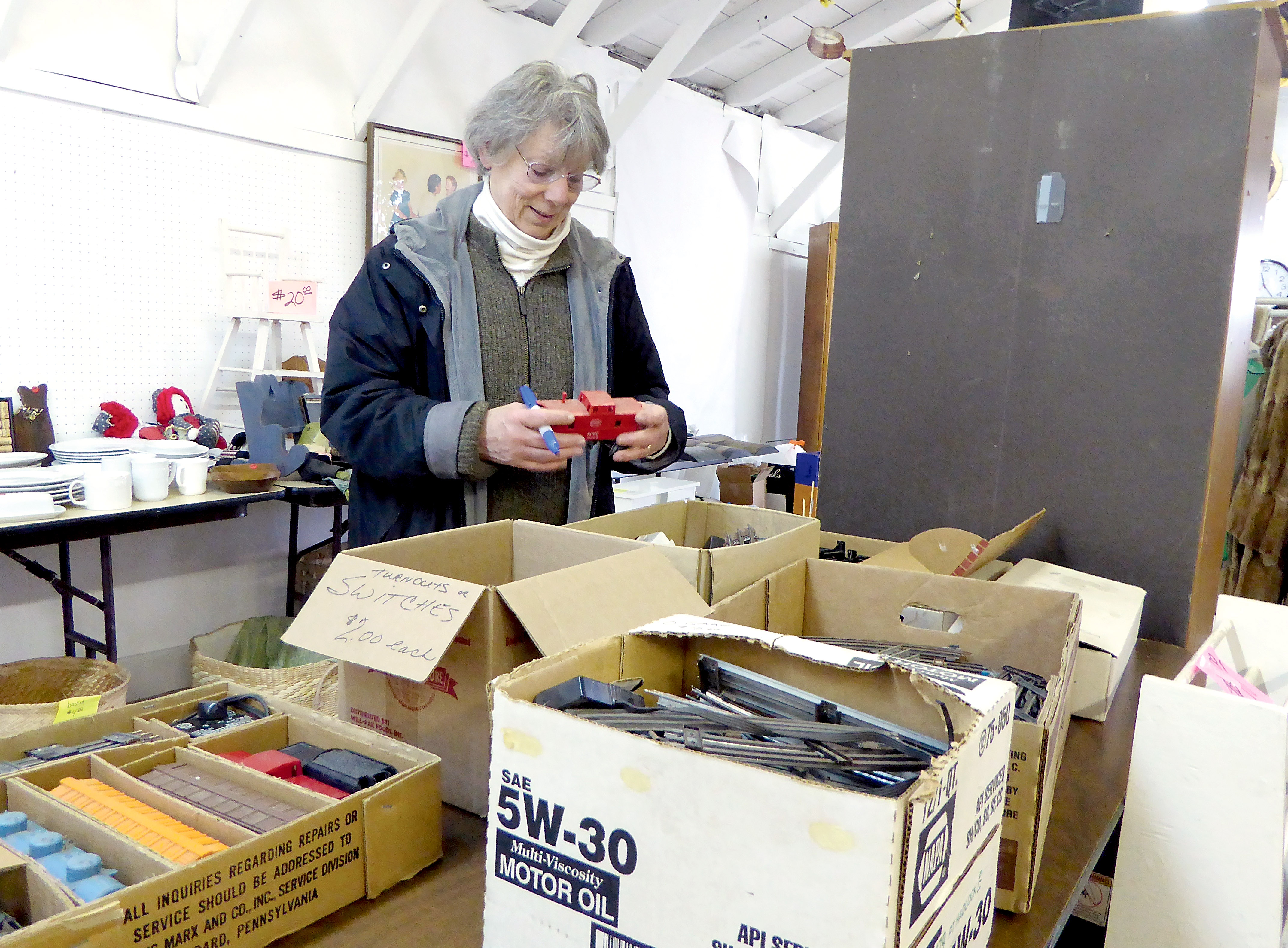Jefferson County Fair Board member Virginia Crandall prices an electric train set in preparation for the fairgrounds' garage sale Saturday. — Charlie Bermant/Peninsula Daily News ()