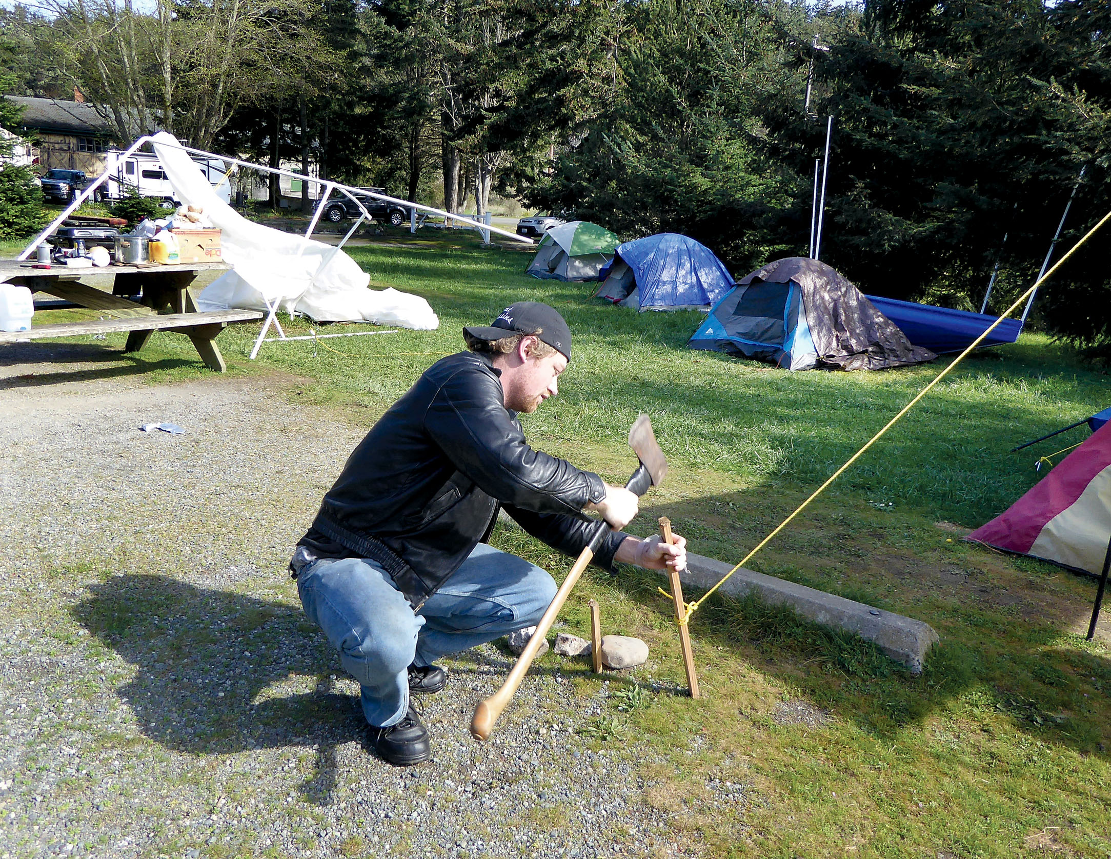 Levi Johnson hammers in the stakes to repair a tent that was blown down during a storm Monday night. Johnson is part of a small tent city in Fort Worden State Park. — Charlie Bermant/Peninsula Daily News ()