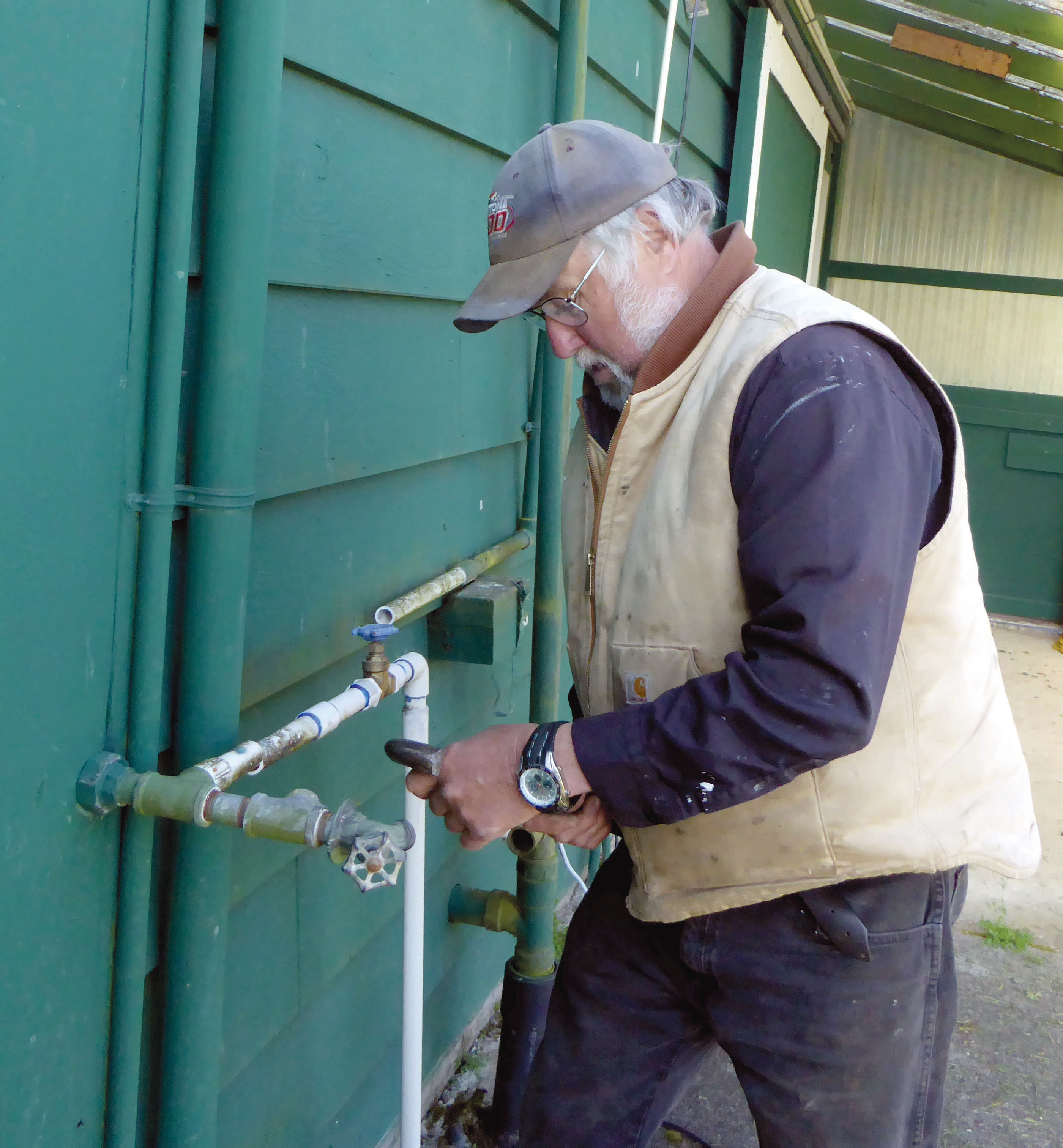 Jefferson County Fairgrounds Manager Bill McIntire repairs a water pipe Monday. McIntire said he won’t stop members of a tent city from camping at the fairgrounds but will not relax the 10-day limit.  —Photo by Charlie Bermant/Peninsula Daily News ()
