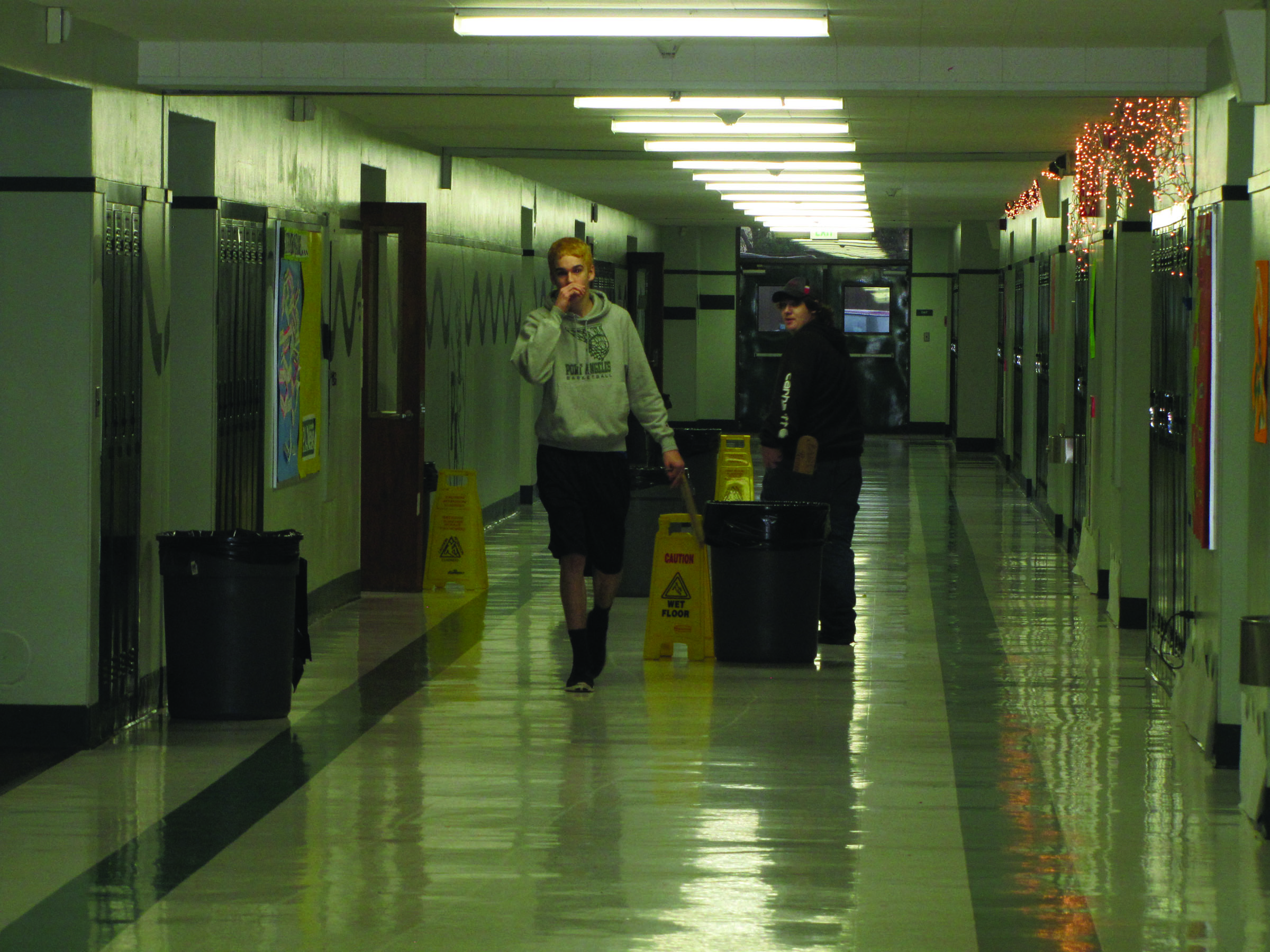 Students walk around trash cans placed in the hallways of Port Angeles High School last December to catch rain water leaking into the building though the failing roof. — Arwyn Rice/Peninsula Daily News ()