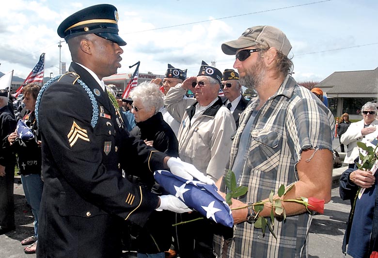U.S. Army Sgt. Will McMillan from Camp Murray presents an American flag to Doug Smith of Sequim during the monthly veterans memorial on Friday at Veterans Park in Port Angeles. Smith's flag