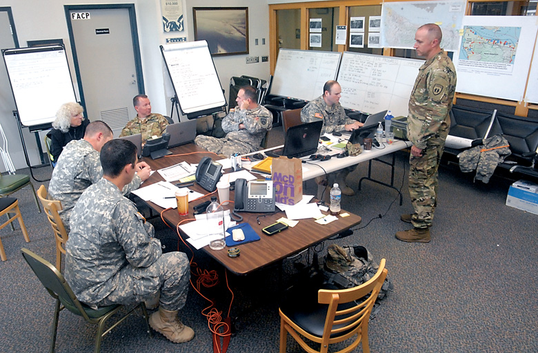 Military personnel with Geographic Task Force 2 take part in a region-wide telephonic briefing from their command post set up in the passenger terminal at William R. Fairchild International Airport in Port Angeles on Thursday as part of the four-day Cascadia Rising earthquake drill. (Keith Thorpe/Peninsula Daily News)
