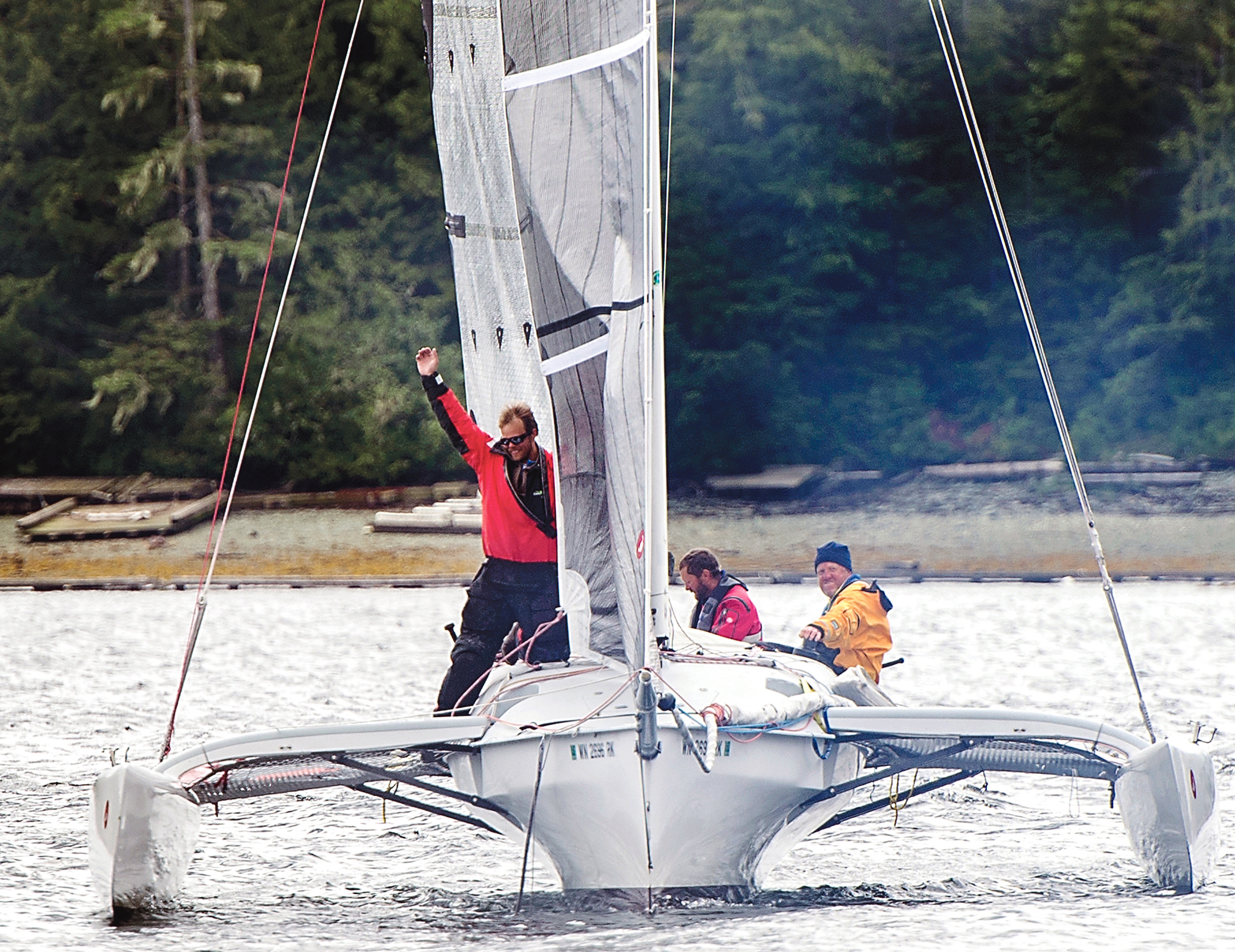 Matt Steverson raises his arm as the Team Elsie Piddock trimaran is first to cross the finish line in the inaugural Race to Alaska that began in Port Townsend. Fellow crew are Graeme Esarey