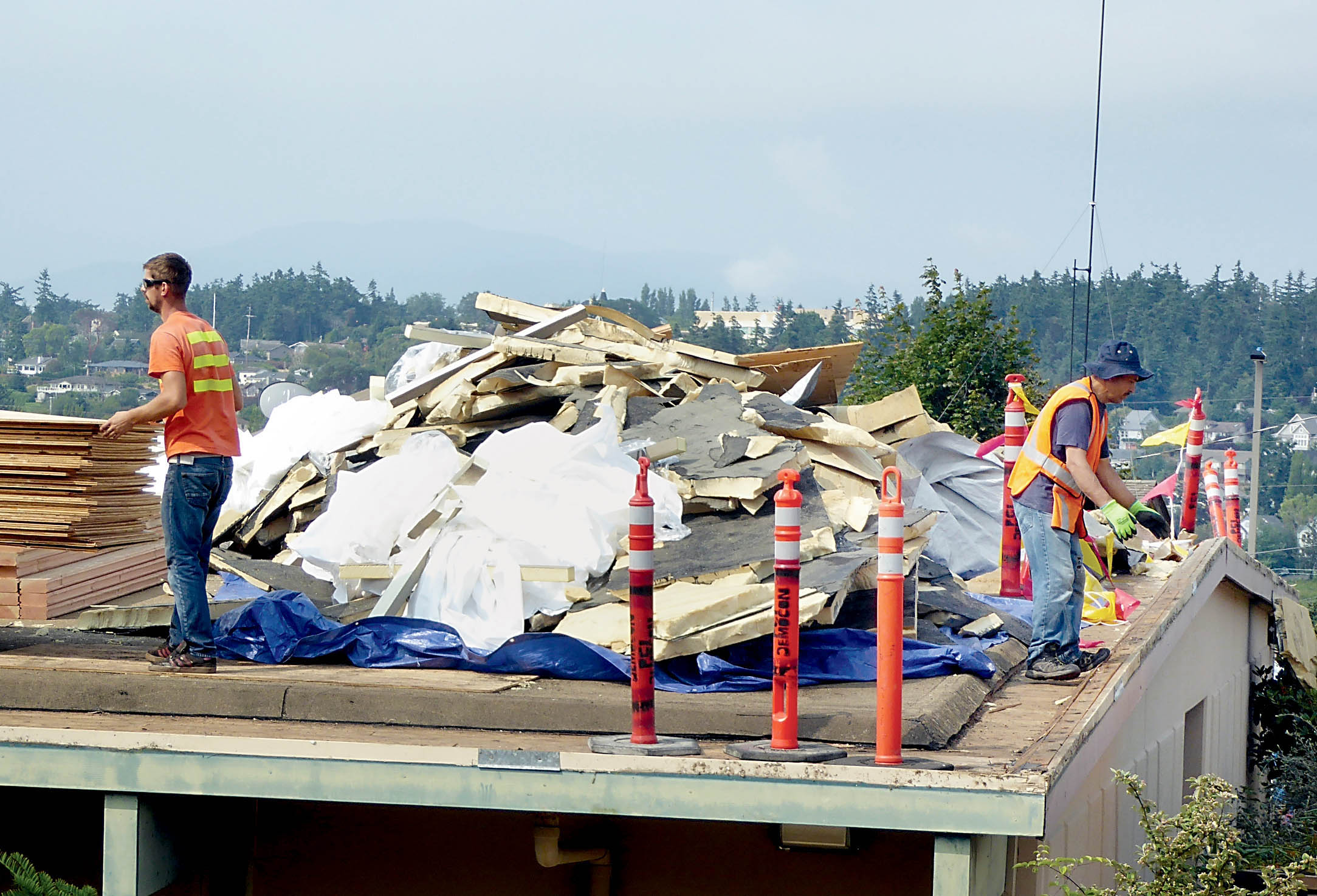 Workers gather debris from the roof at Mountain View Commons during its replacement process
