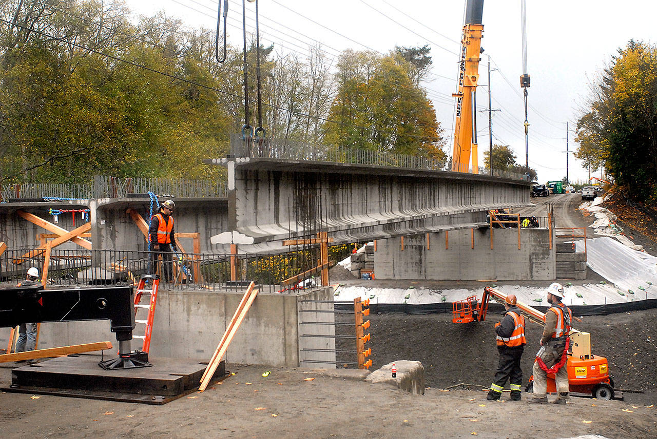 A crew from Ness Cranes of Seattle hoists the last of four 148-foot reinforced concrete beams into place Thursday for what will become the new Old Olympic Highway bridge spanning McDonald Creek west of Sequim. The new bridge replaces a narrower 1957-vintage span considered too narrow and inadequate for modern traffic. Completion of the project, coordinated by Tacoma-based Orion Marine Contractors Inc., is expected in late winter. (Keith Thorpe/Peninsula Daily News)