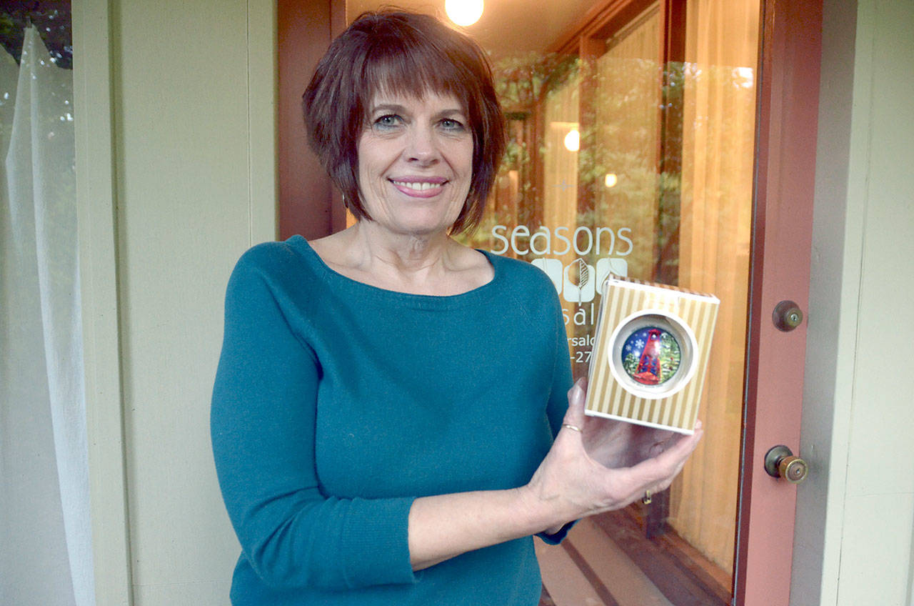 Jolene Sunding holds up this year’s Main Street ornament, which is based off her watercolor painting. (Cydney McFarland/Peninsula Daily News)