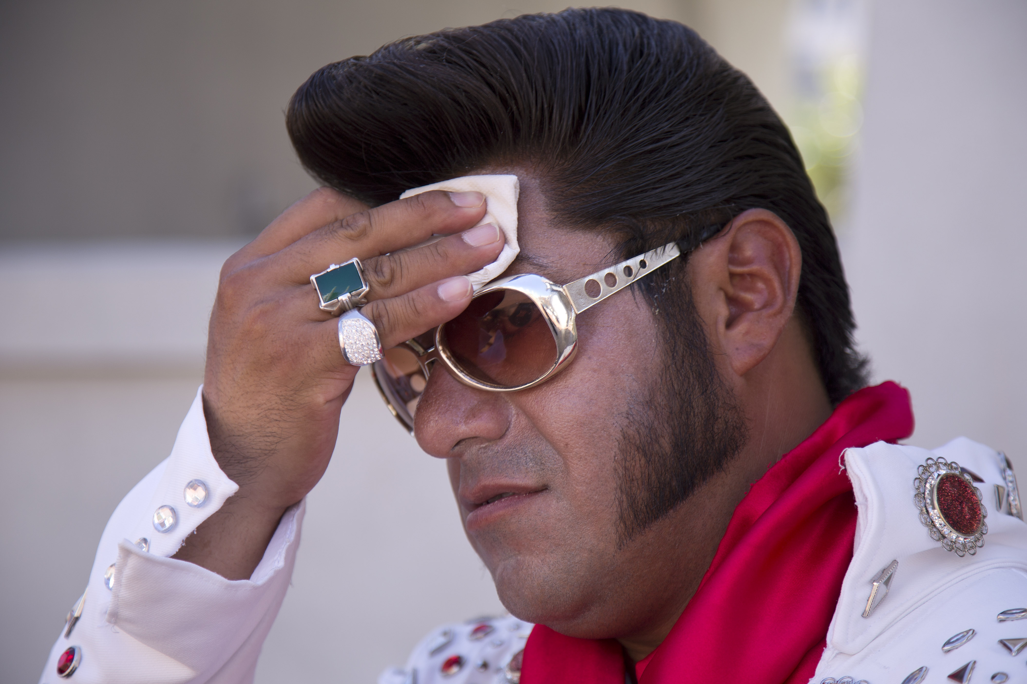 Elvis impersonator Cristian Morales wipes sweat from his brow while standing out on the Las Vegas Strip posing for photos with tourists. The Associated Press