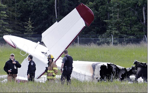 Police and emergency personnel stand near the remains of a fixed-wing aircraft that was engulfed in flames Sunday at the Soldotna Airport in Soldotna