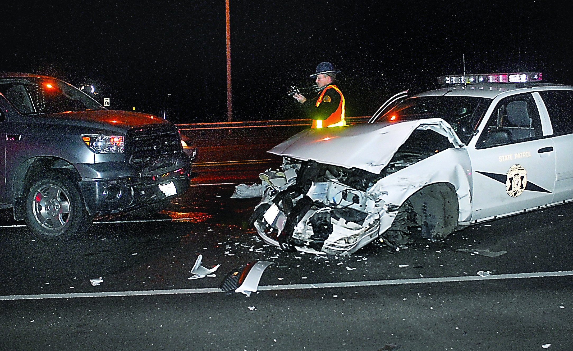 State Patrol Trooper Keith Nestor takes photos to document a collision involving a State Patrol cruiser and other vehicles Friday near Port Angeles. The driver of the patrol car was not identified. Keith/Thorpe/Peninsula Daily News