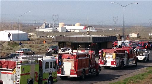 A line of emergency vehicles line a roadway in sight of the Williams Northwest Pipeline plant in the distance. Tri-City Herald via The Associated Press