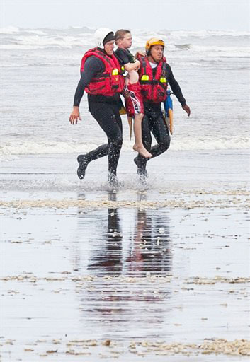 Coast Guard surf rescue swimmers Julez Orr and Eddie Mendez carry a 9-year-old Chimacum boy from the ocean Thursday. His sister remains lost in the water. Damian Mulinix/Chinook Observer