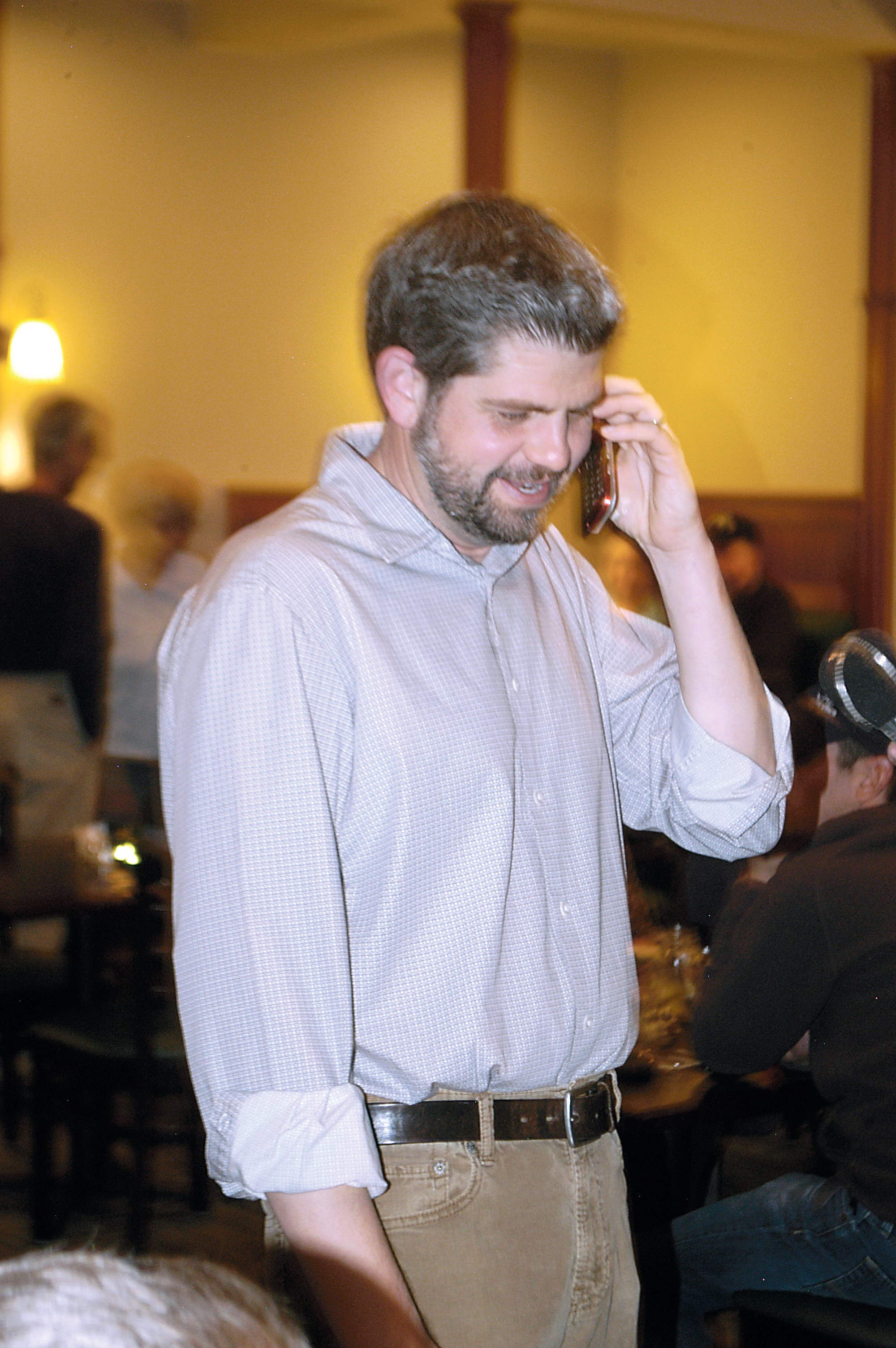 Mark Ozias joyfully informs his father over the phone he has garnered over 50 percent of ballots in the first count Tuesday evening at the Emerald Northwest Grill & Public House in Sequim. Chris McDaniel/Peninsula Daily News
